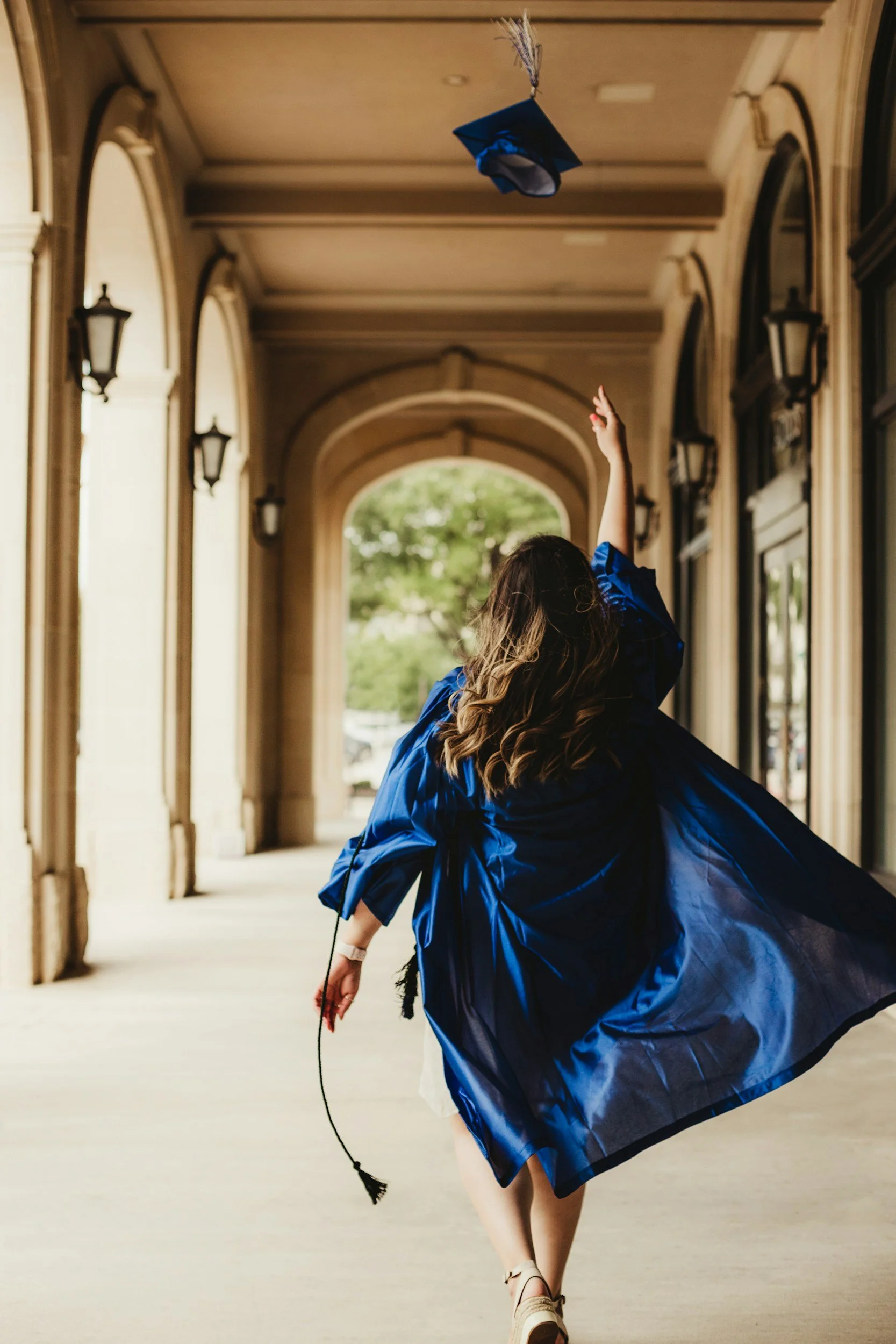 Graduate tosses her cap as she walks down corridor in Kansas City.