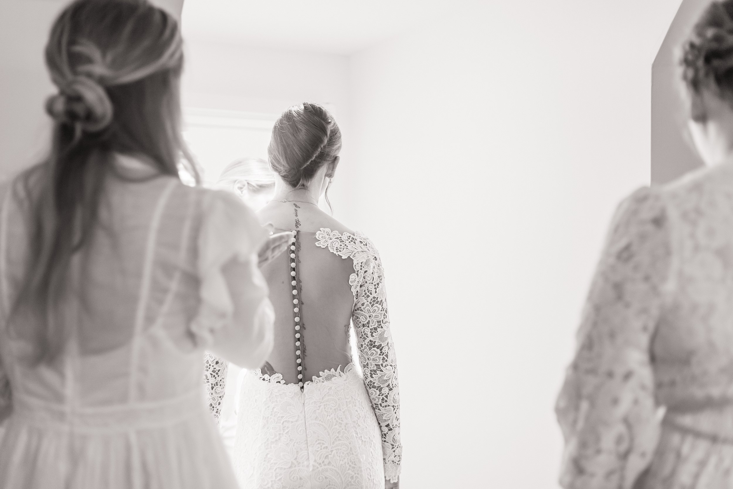 Bride and sisters stand by window during private estate wedding in Olathe, KS.
