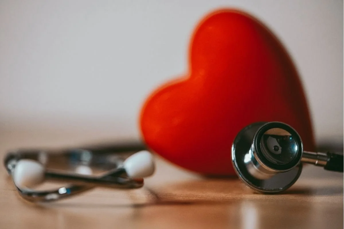 A red heart in the background and a stethoscope in the foreground