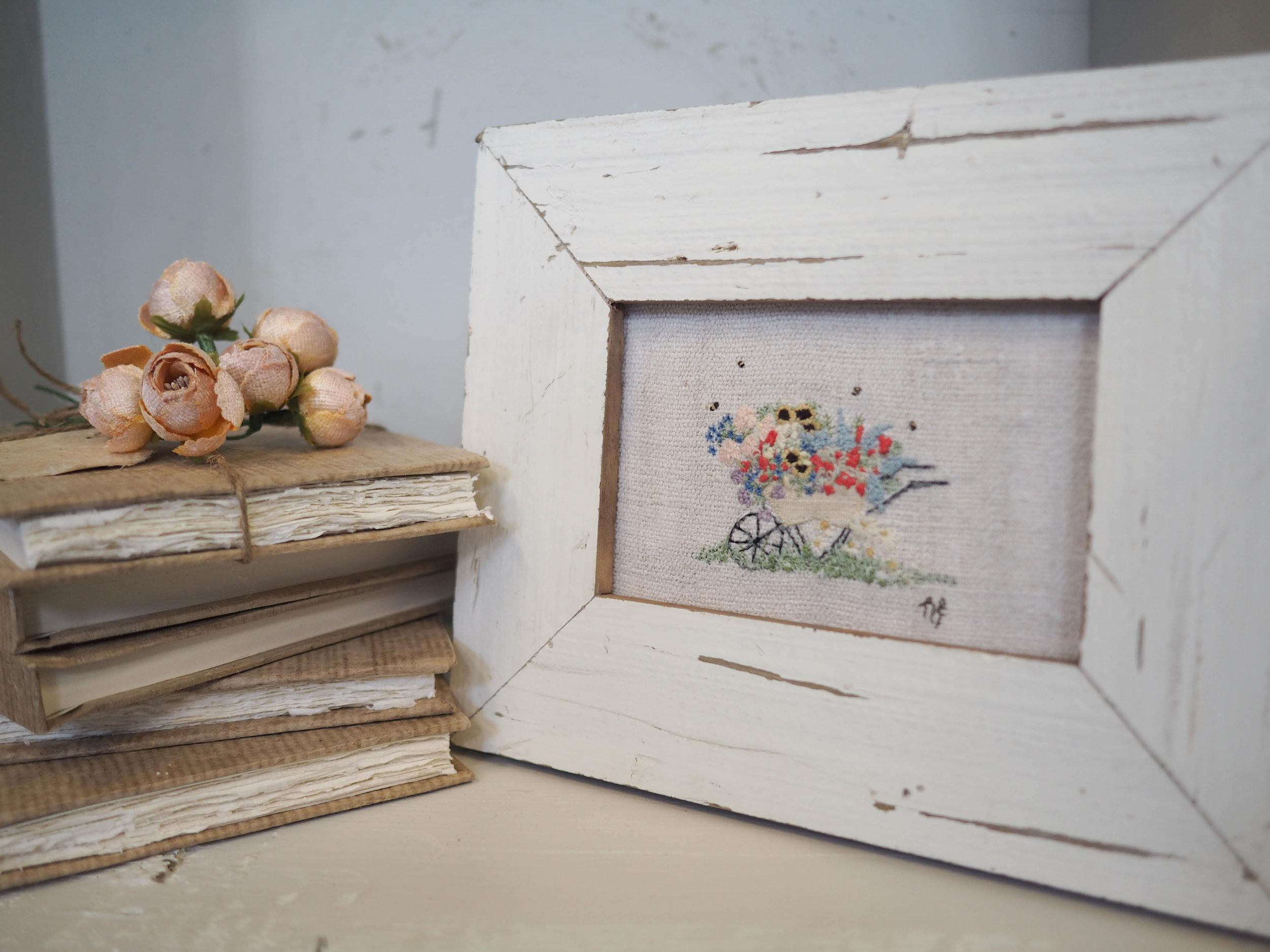 A stack of notebooks with beautiful handmade paper and my 'Day at the Allotment' embroidery framed with reclaimed wood.