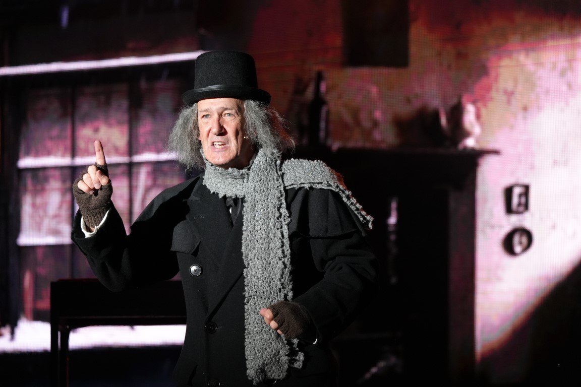 scrooge-2023-ebenezer-scrooge-top-hat-grey-scarf-raises-finger-aberdeen-arts-centre.jpg