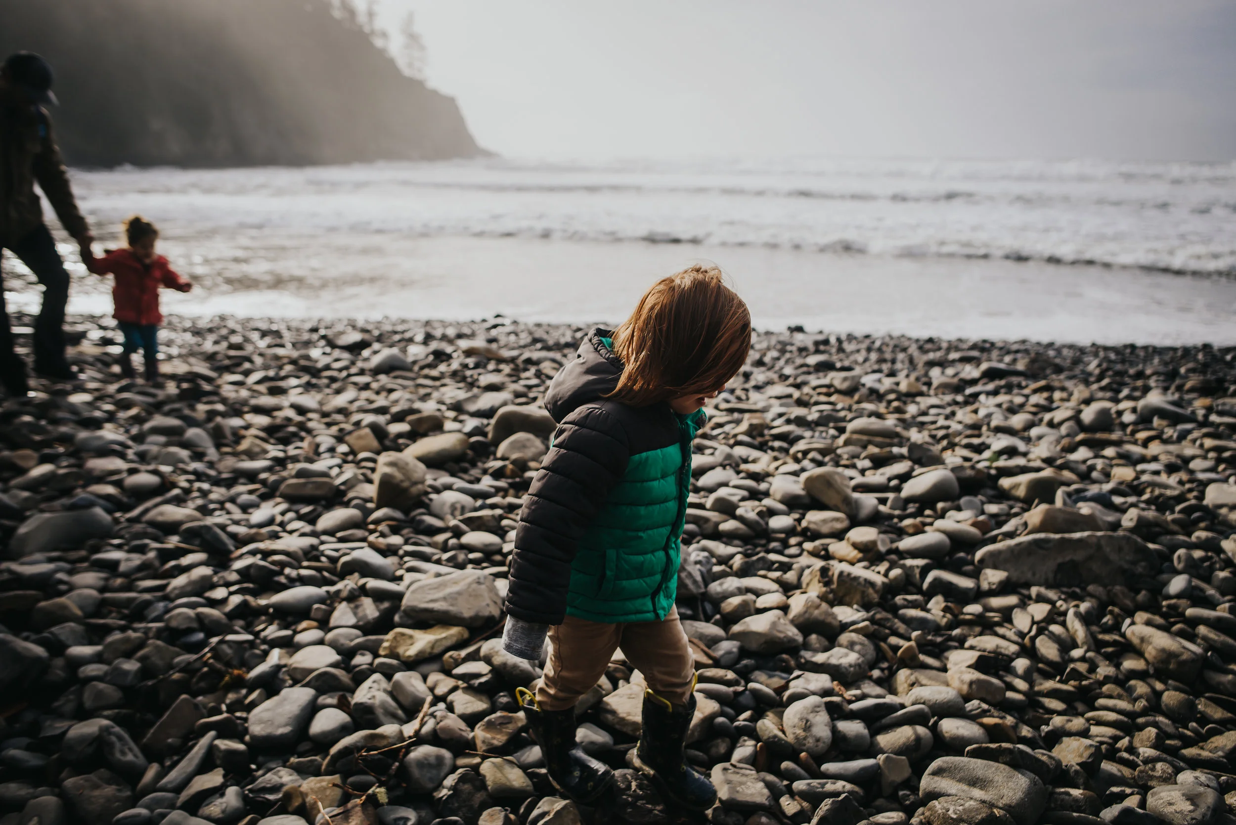 Little boy hikes on rocks near the ocean in Oswald West State Park.
