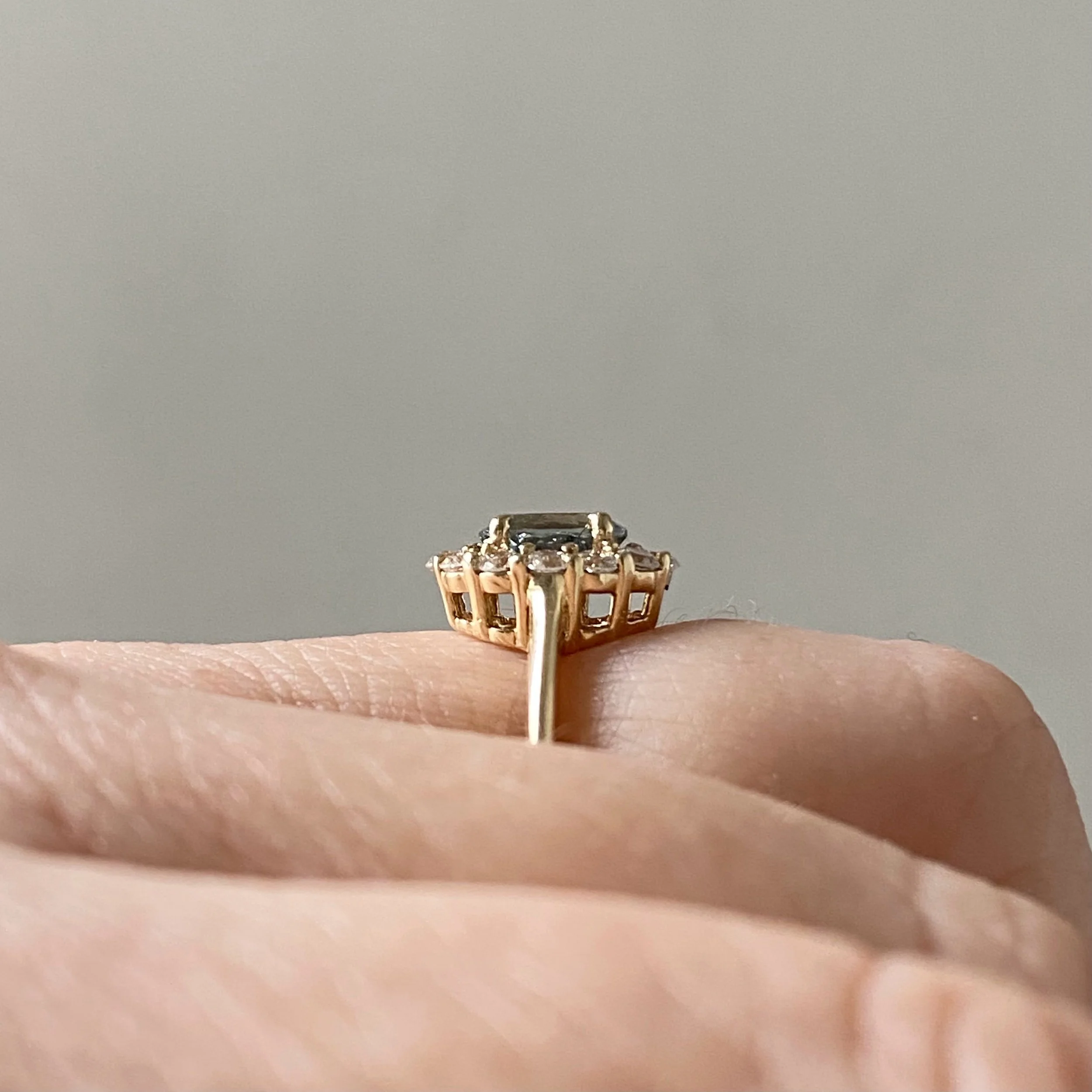 oval blue green spinel claw set in a Canadian diamond halo engagement ring 14k yellow gold side view on hand Kim Drosdick Jewellery