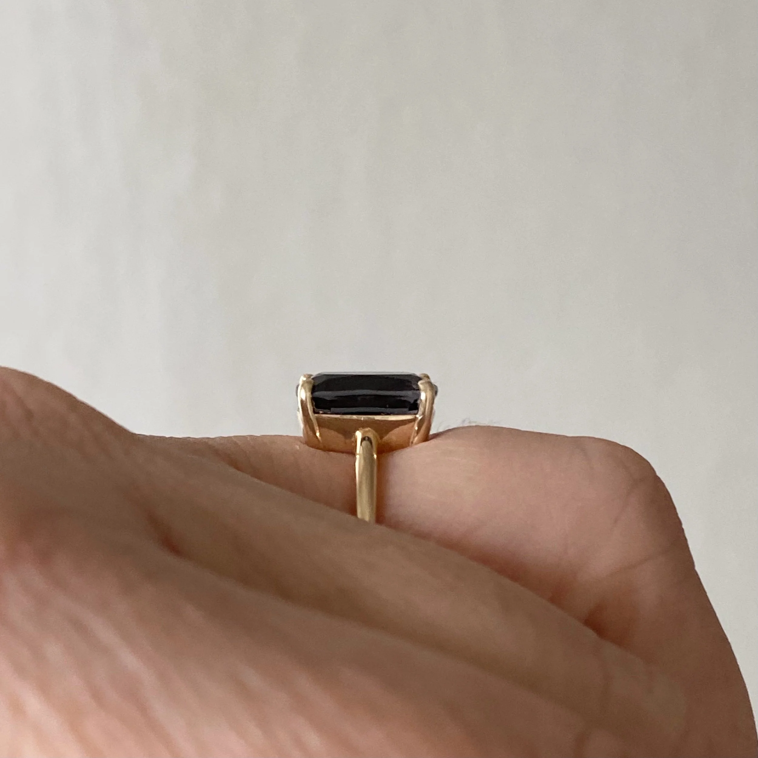 elongated cushion dark blue purple spinel claw set solitaire 14k yellow gold engagement ring on hand side view Kim Drosdick Jewellery Toronto