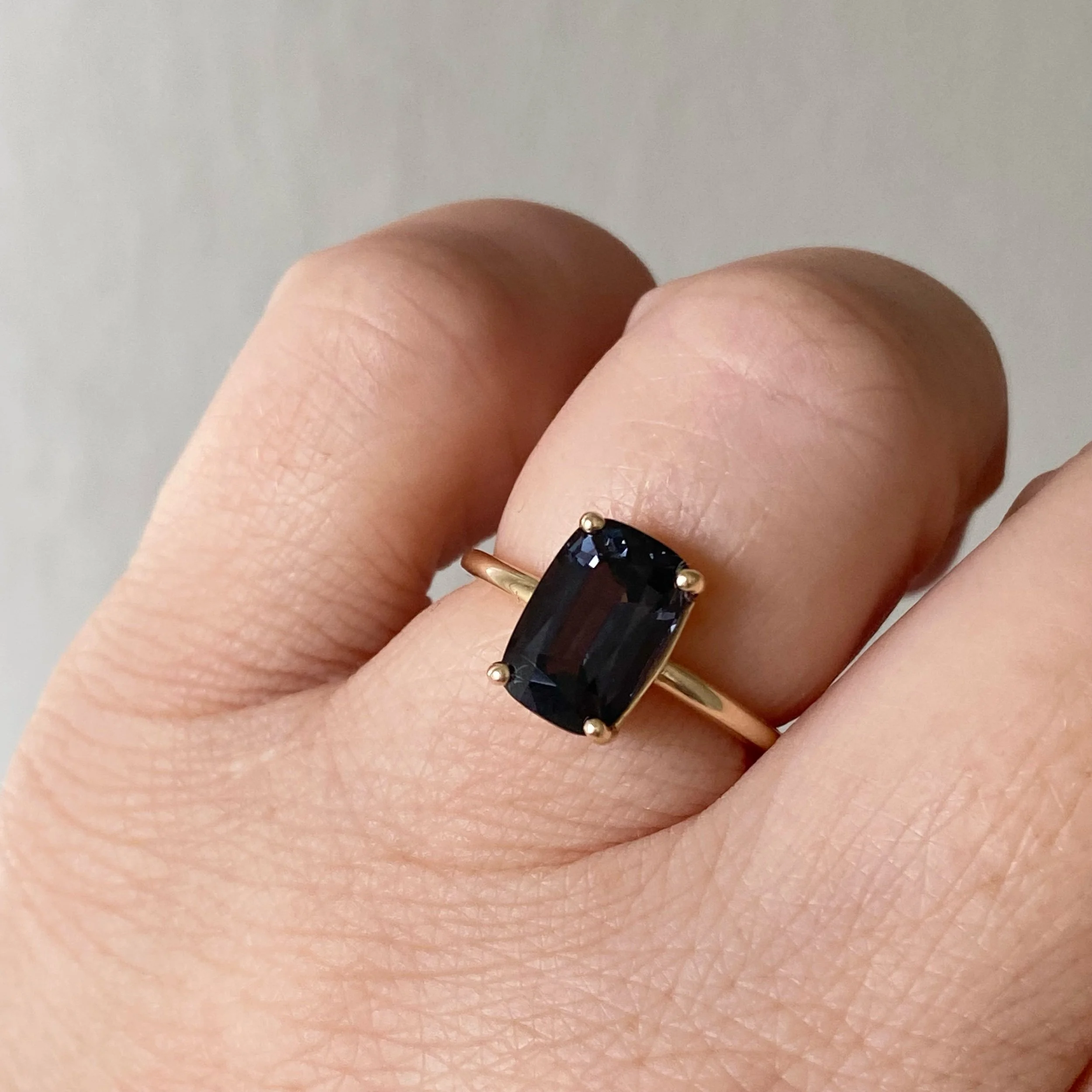 elongated cushion dark blue purple spinel claw set solitaire engagement ring 14k yellow gold engagement ring on hand Kim Drosdick Jewellery Toronto