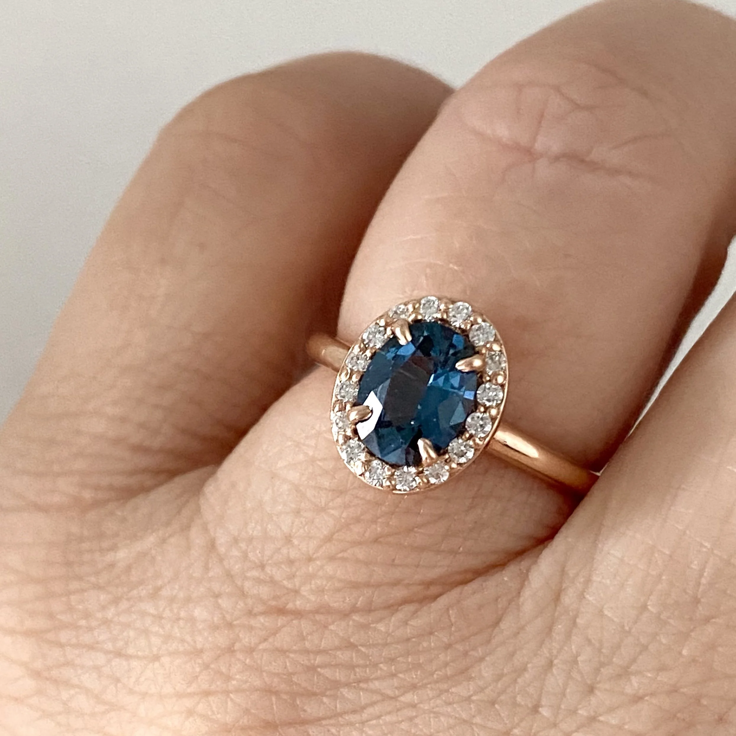 gorgeous oval blue spinel centre stone Canadian diamond halo engagement ring 14k rose gold on hand Kim Drosdick Jewellery