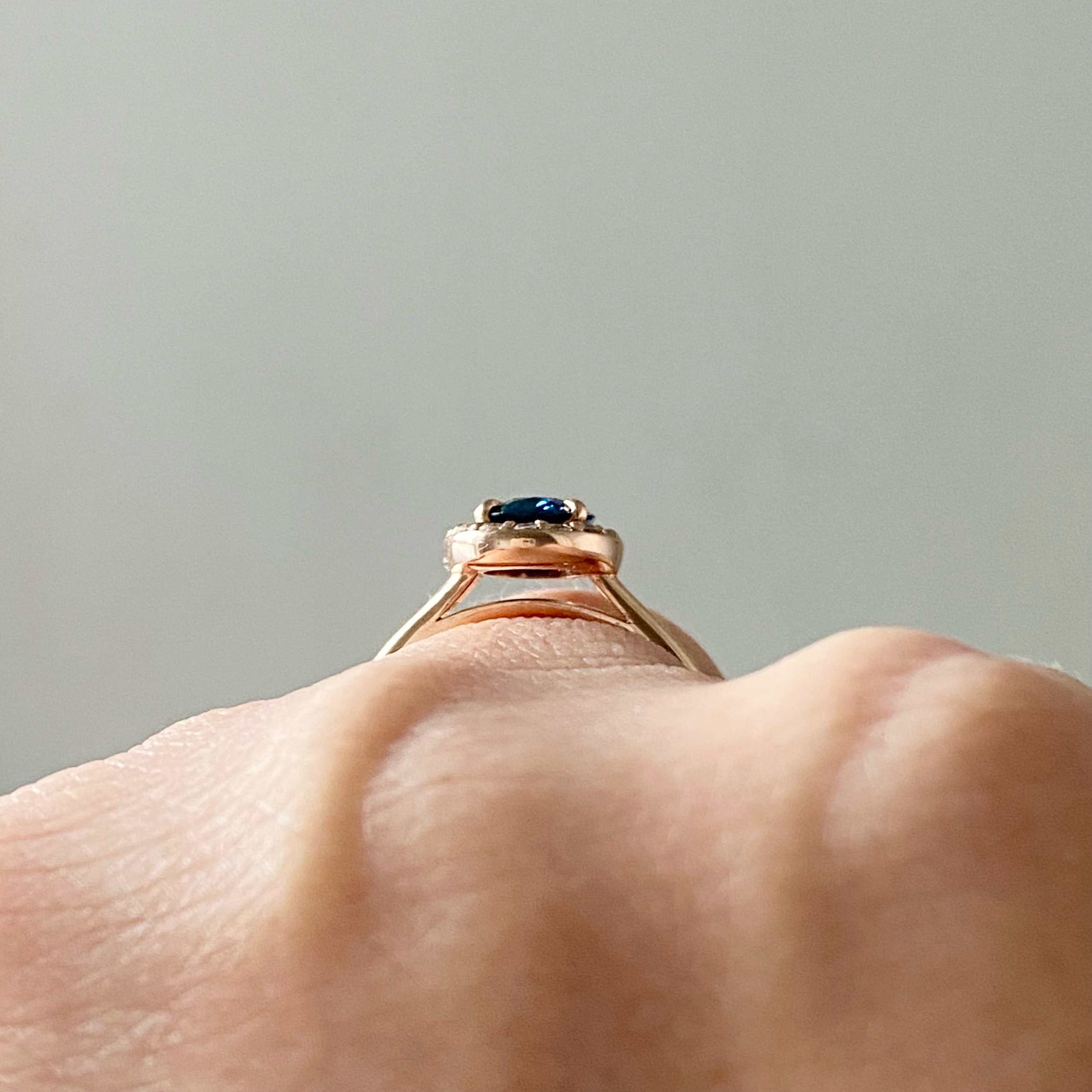 gorgeous oval blue spinel centre stone Canadian diamond halo engagement ring 14k rose gold on hand through finger view Kim Drosdick Jewellery