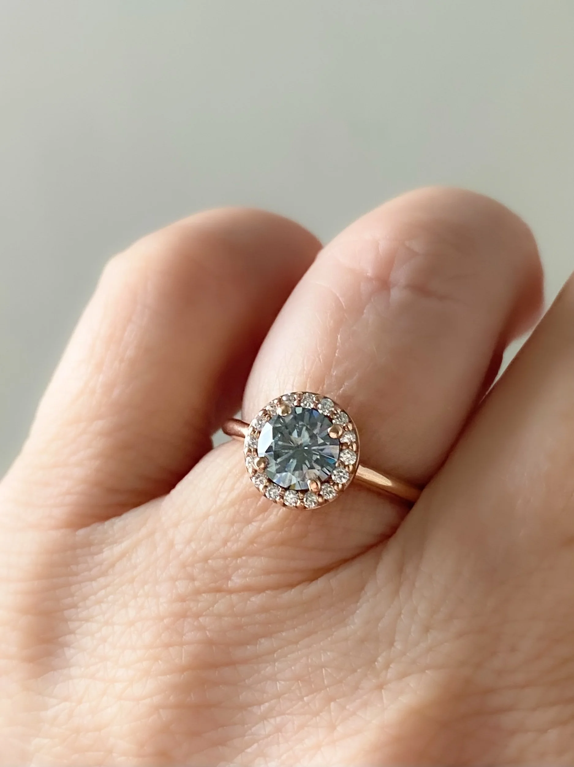 round brilliant cut grey moissanite canadian diamond halo 14k rose gold engagement ring on hand Kim Drosdick Jewellery