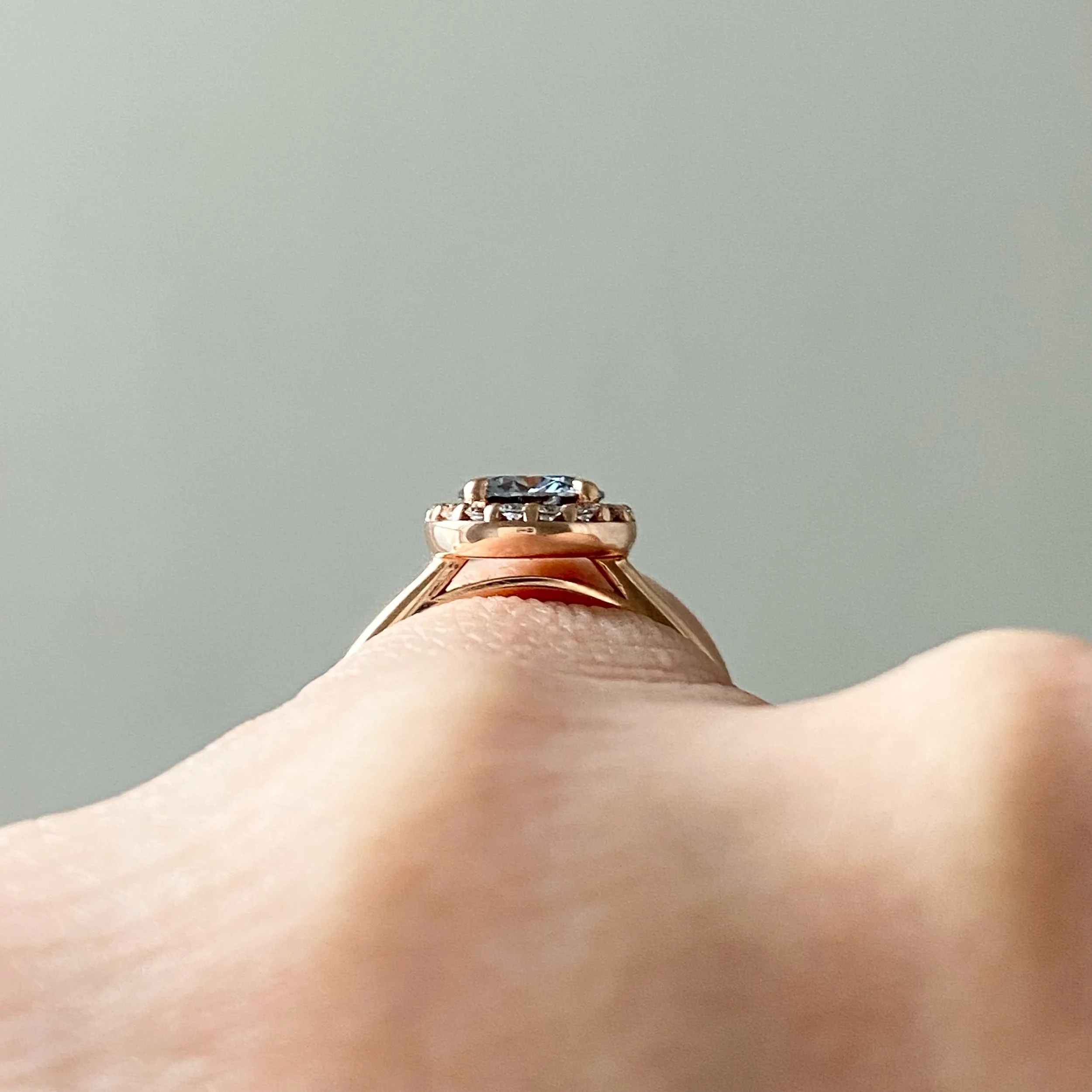 round brilliant cut grey moissanite canadian diamond halo 14k rose gold engagement ring through finger view Kim Drosdick Jewellery