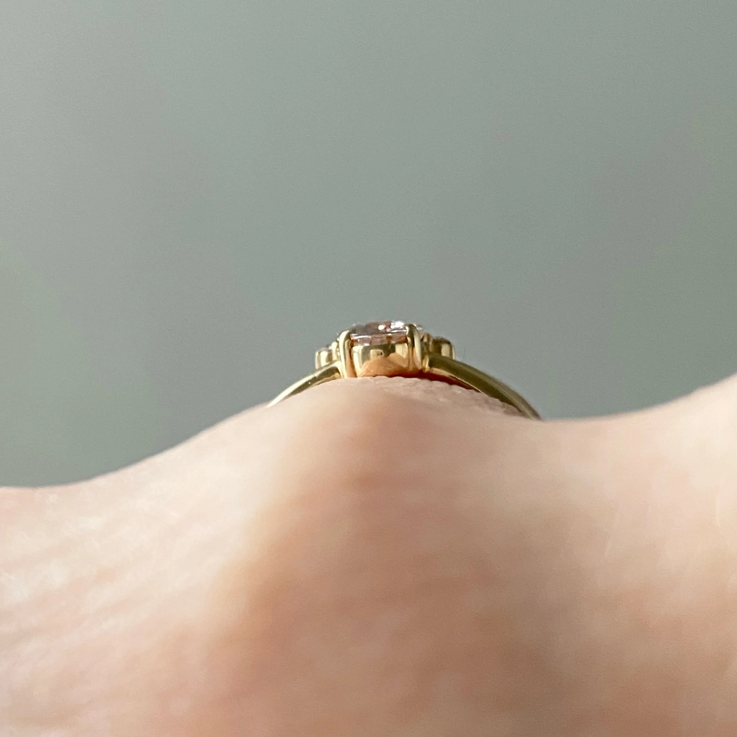 peachy pink oval morganite with little crown of Canadian diamonds claw set in 14k yellow gold narrow rounded band through finger view Kim Drosdick Jewellery Toronto
