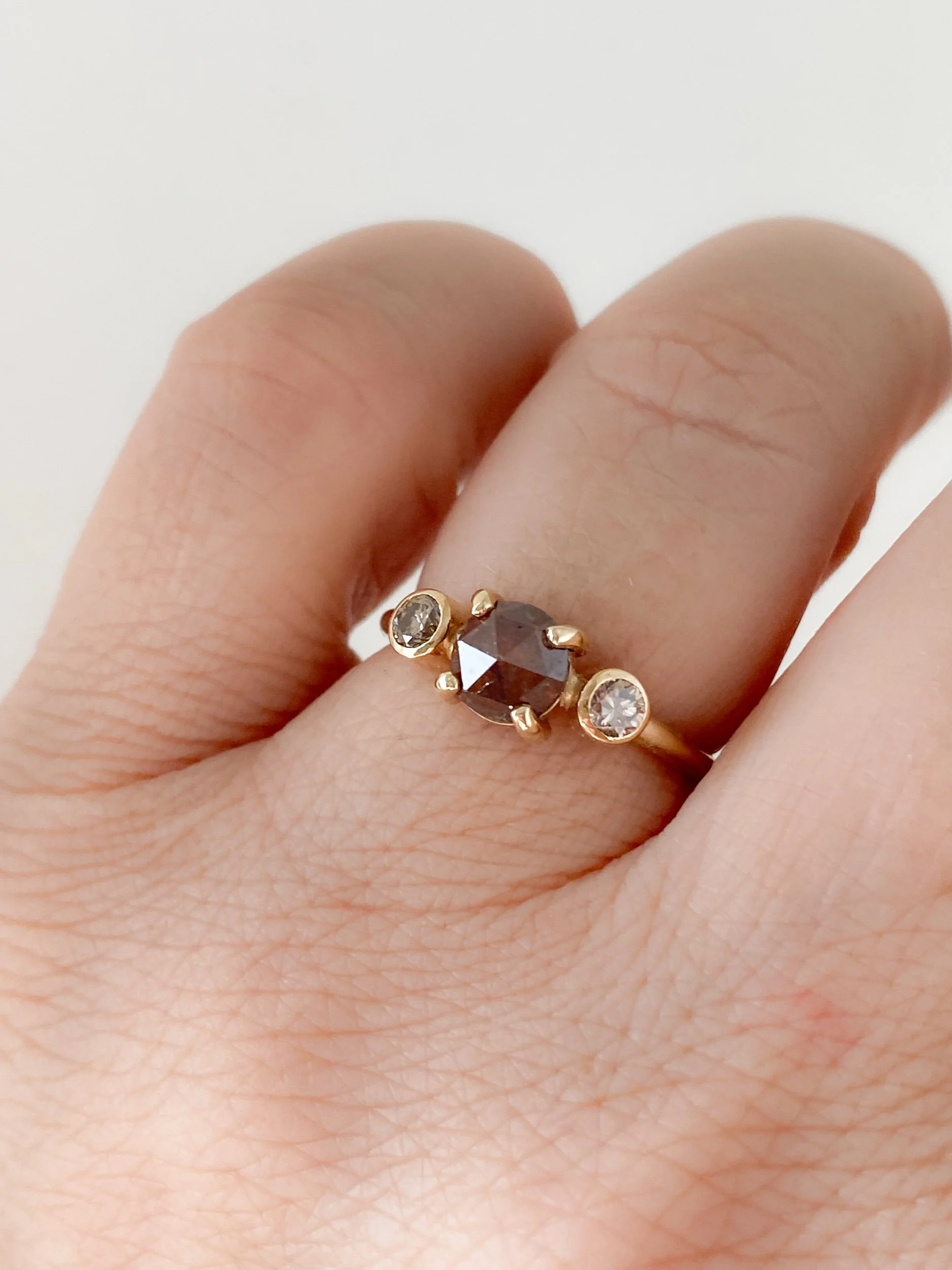 round deep red rose cut claw set diamond flanked by bezel set champagne brilliant cut diamonds 14k yellow gold on hand Kim Drosdick Jewellery Toronto