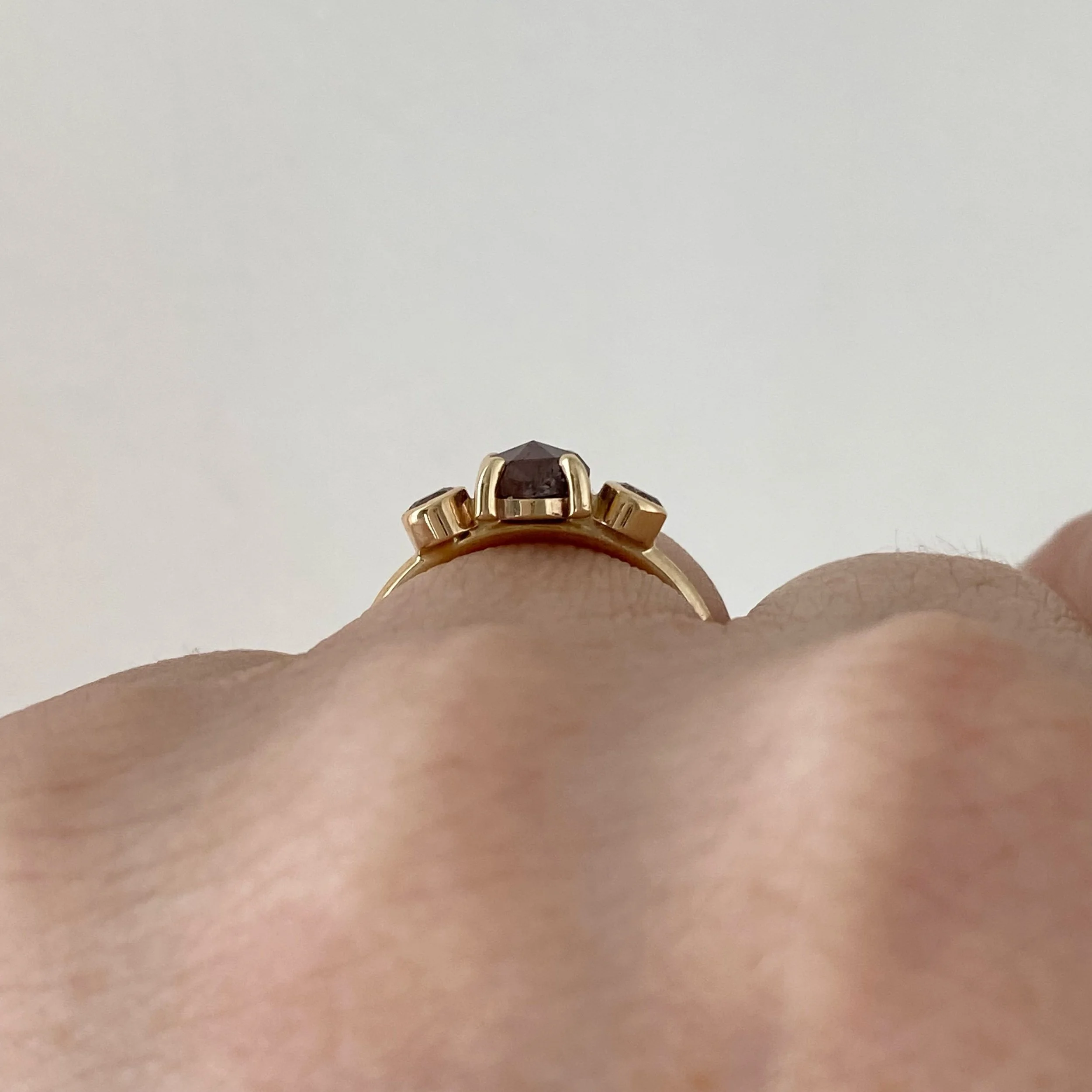 dark grey rose cut diamond engagement ring with diamond trio triangle sides 14k yellow gold through finger  view on hand Kim Drosdick Jewellery Toronto