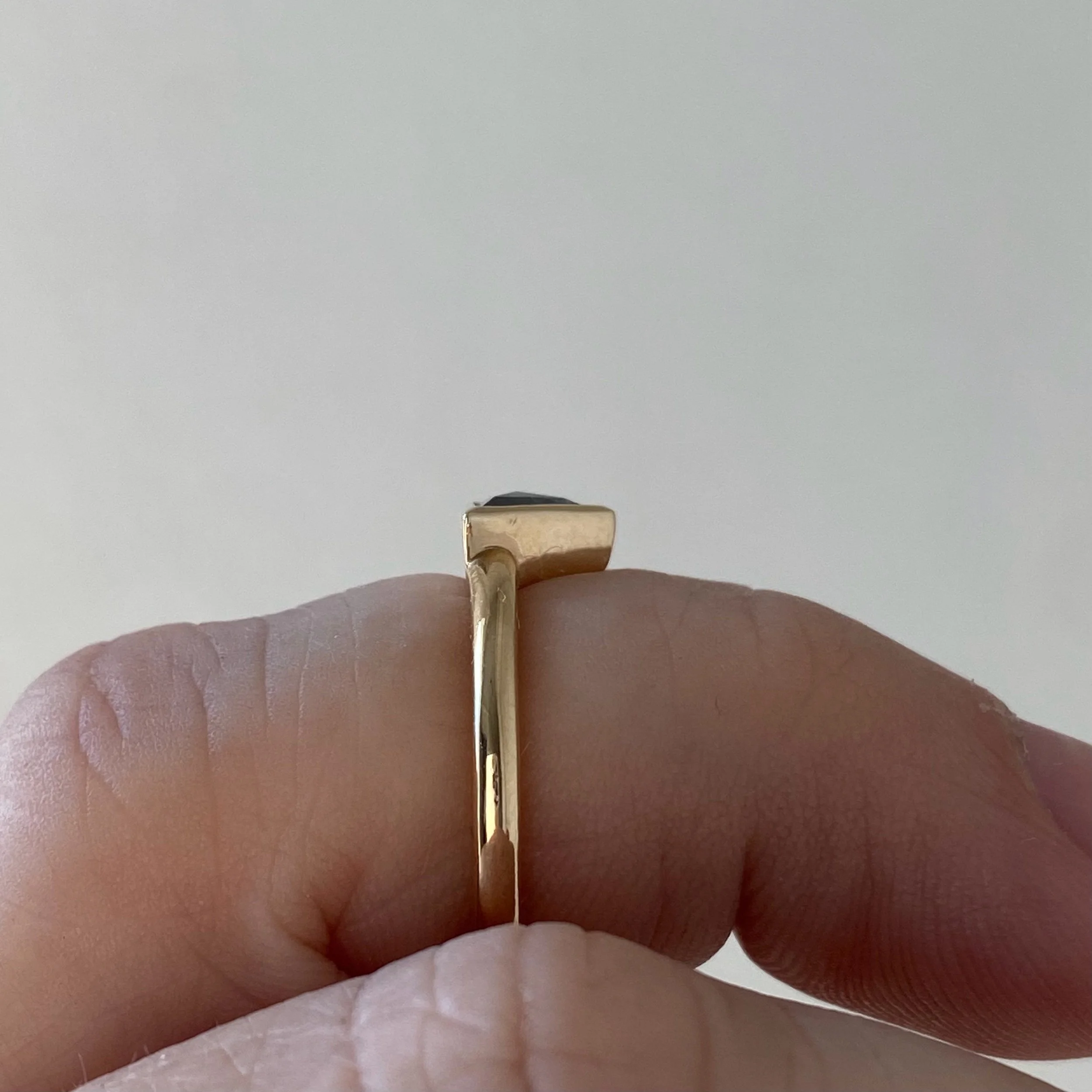 darker triangle salt and pepper diamond bezel set off side bottom justified to round wire band 14k yellow gold side finger view on hand Kim Drosdick Jewellery Toronto