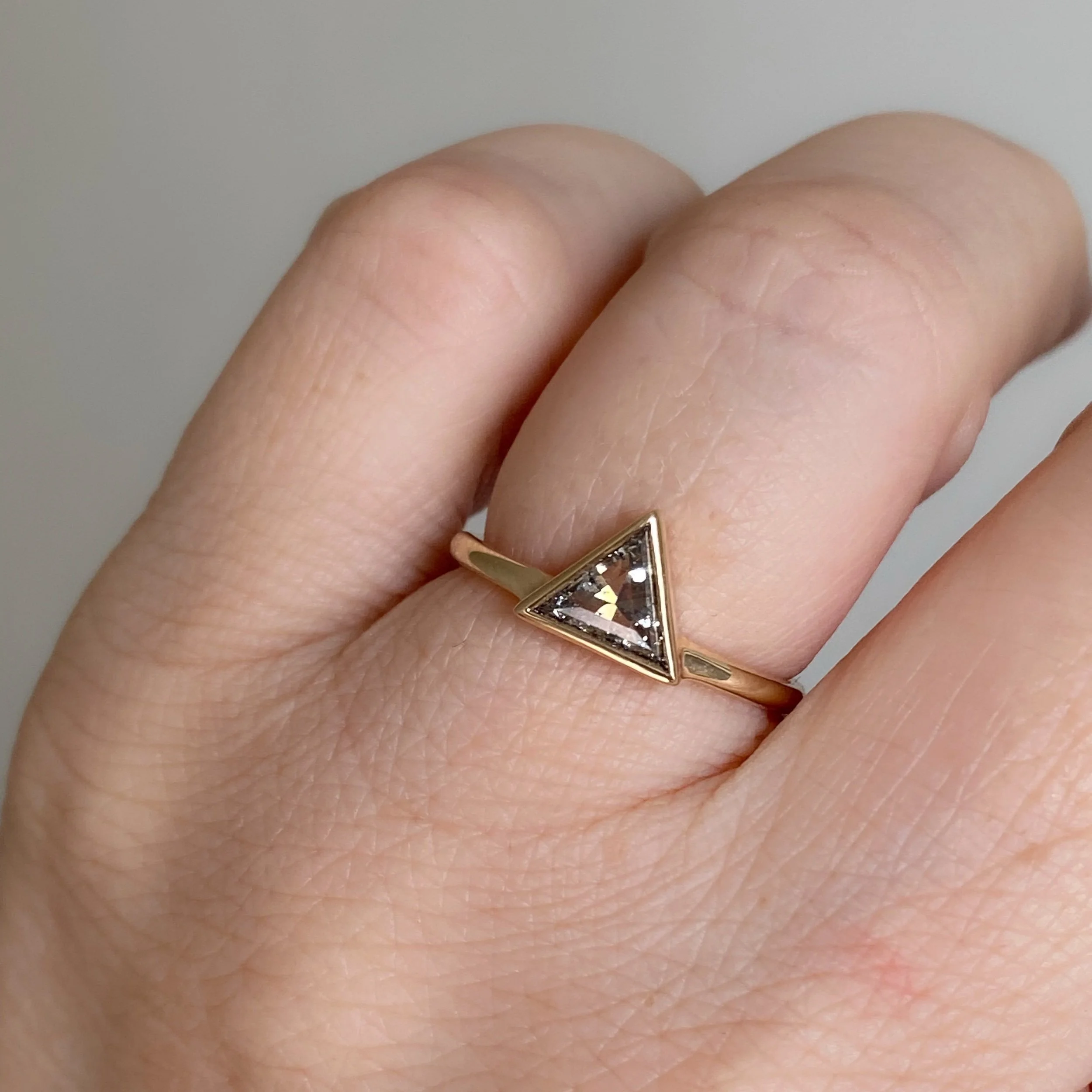 clearer larger triangle salt and pepper diamond bezel set off side bottom justified to round wire band 14k yellow gold on hand Kim Drosdick Jewellery Toronto