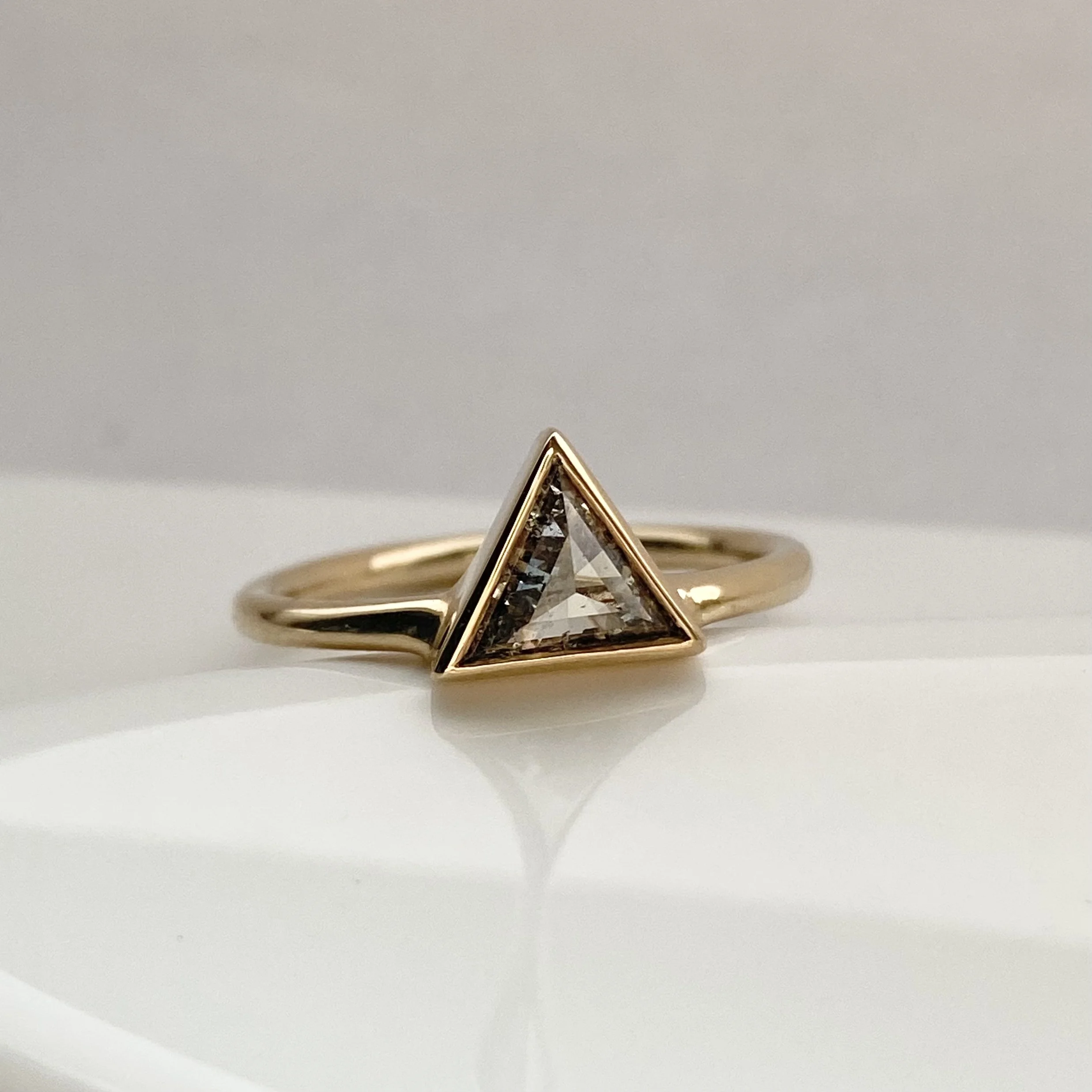 clearer larger triangle salt and pepper diamond bezel set off side bottom justified to round wire band 14k yellow gold on dish Kim Drosdick Jewellery Toronto