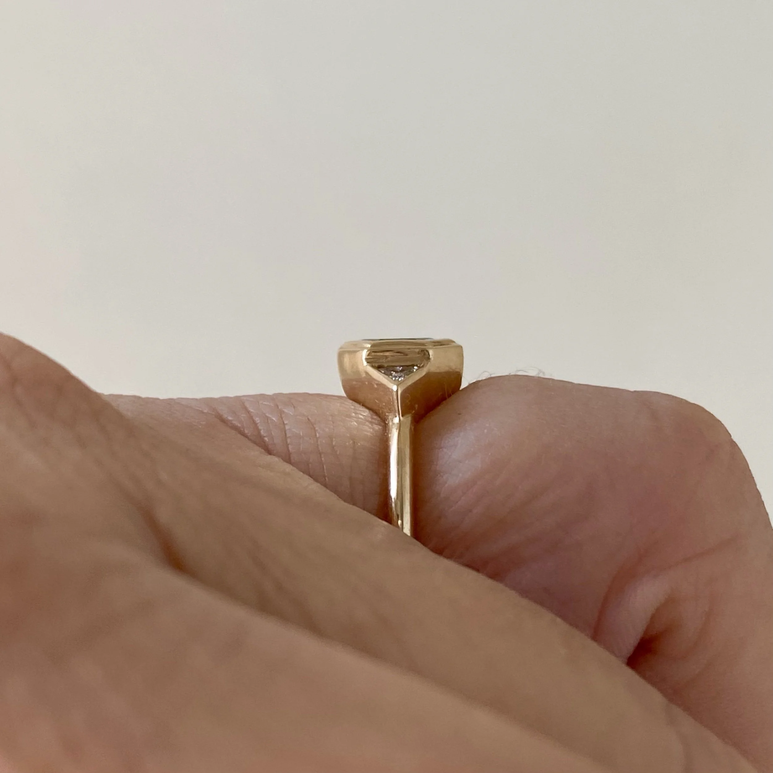 dark teak hexagonal spinel 3 stone engagement ring bezel settings rounded narrow band 14k yellow gold side finger view on hand Kim Drosdick Jewellery Toronto