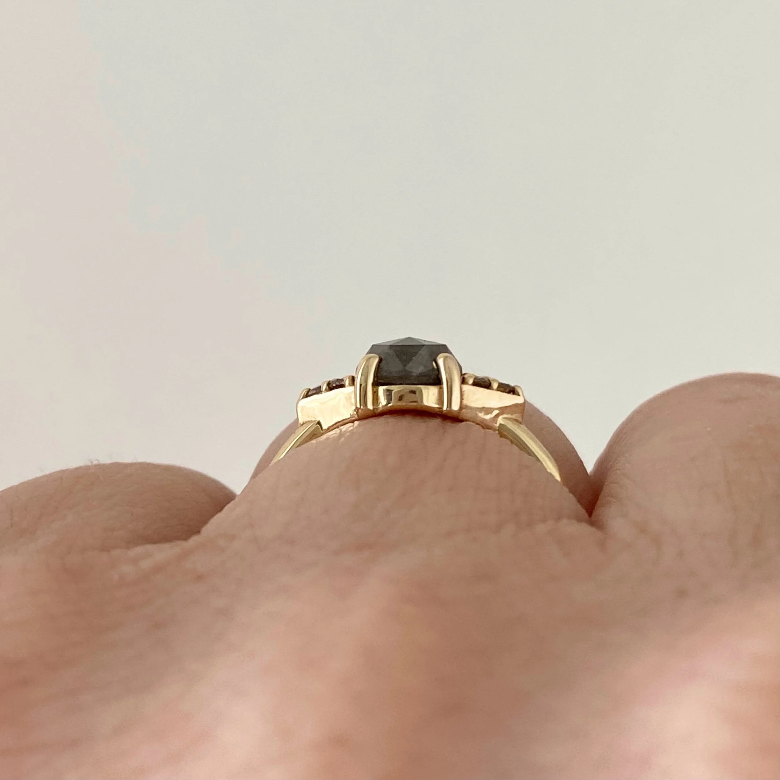 dark grey rose cut diamond engagement ring with diamond trio triangle sides 14k yellow gold front view on hand Kim Drosdick Jewellery Toronto on hand side view