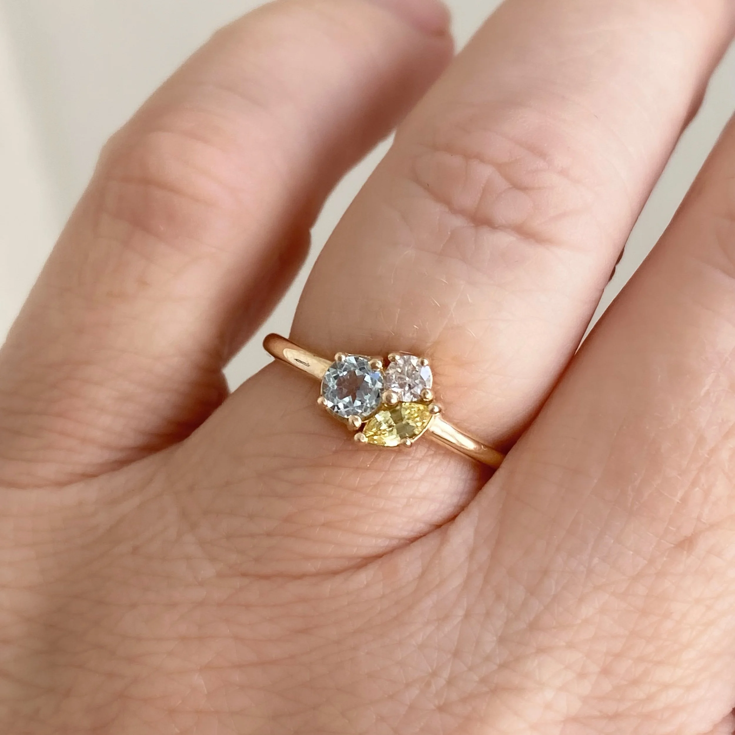 three stone cluster ring in 14k recycled yellow gold using aquamarine diamond and yellow sapphire  sits low to the hand on model