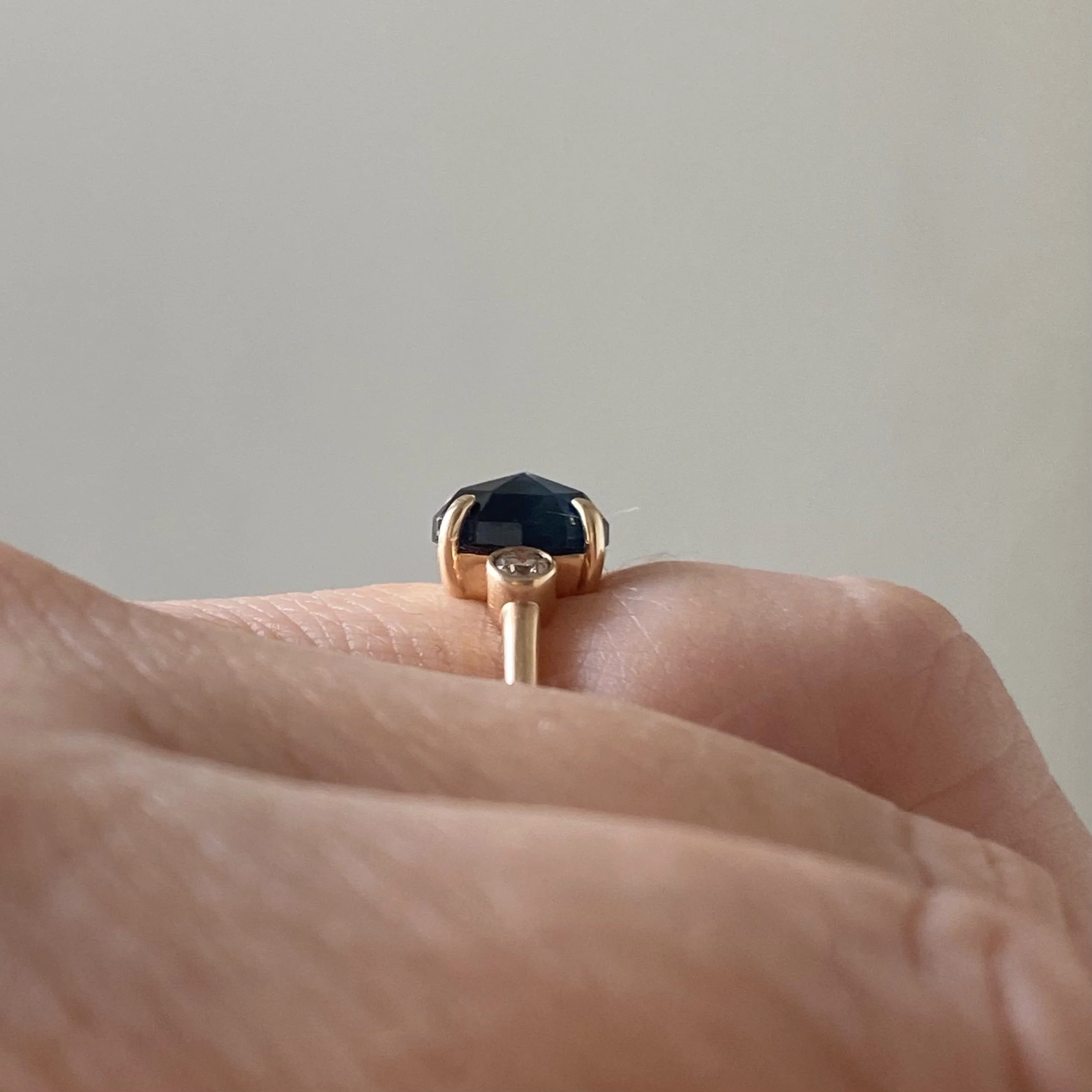 rose cut blue oval sapphire 3-stone champagne diamond alternative engagement ring 14k yellow gold bezel set claw set rounded band Kim Drosdick Jewellery Toronto on hand side view