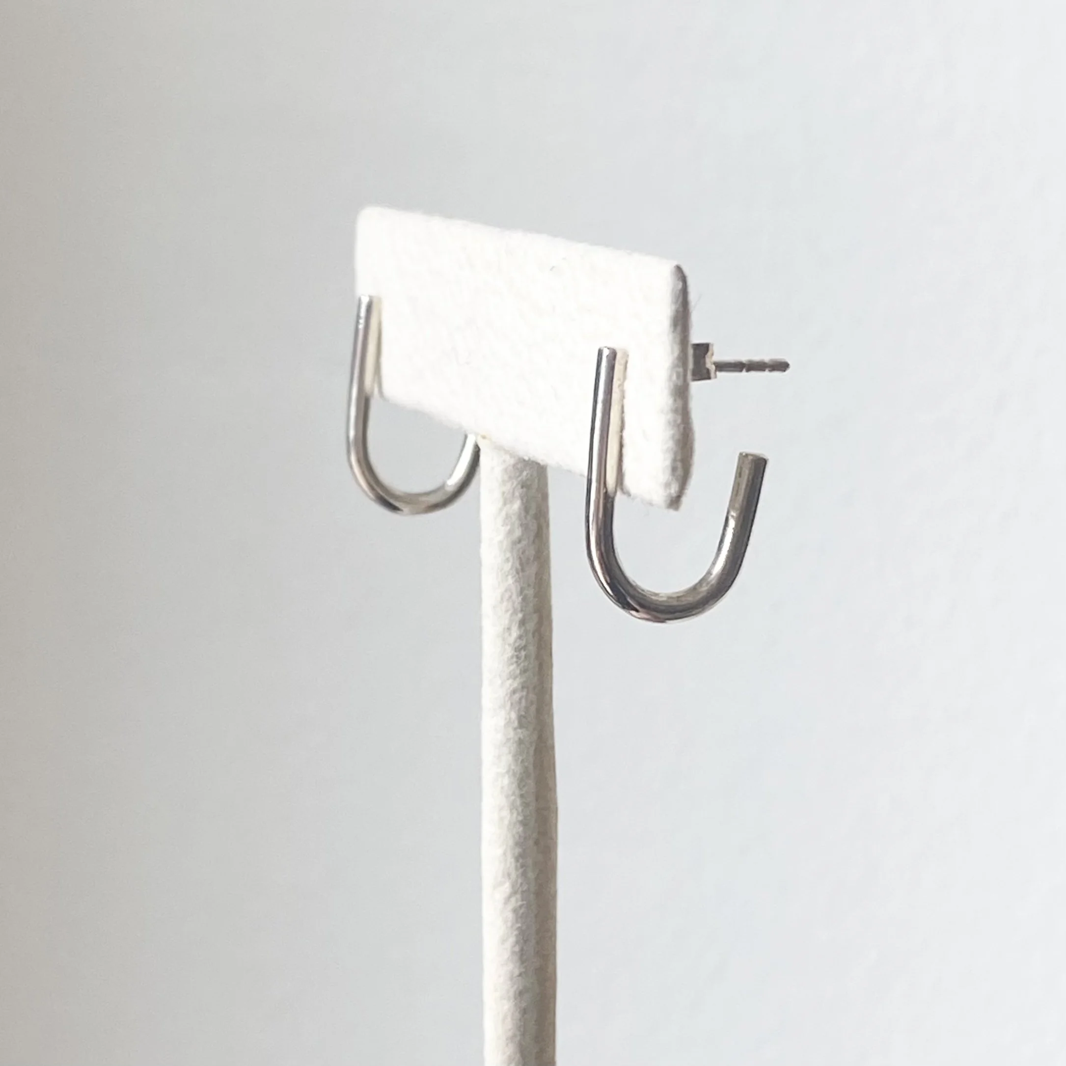 sterling silver round wire j hoop earrings on stand polished studs side view Kim Drosdick Jewellery Toronto