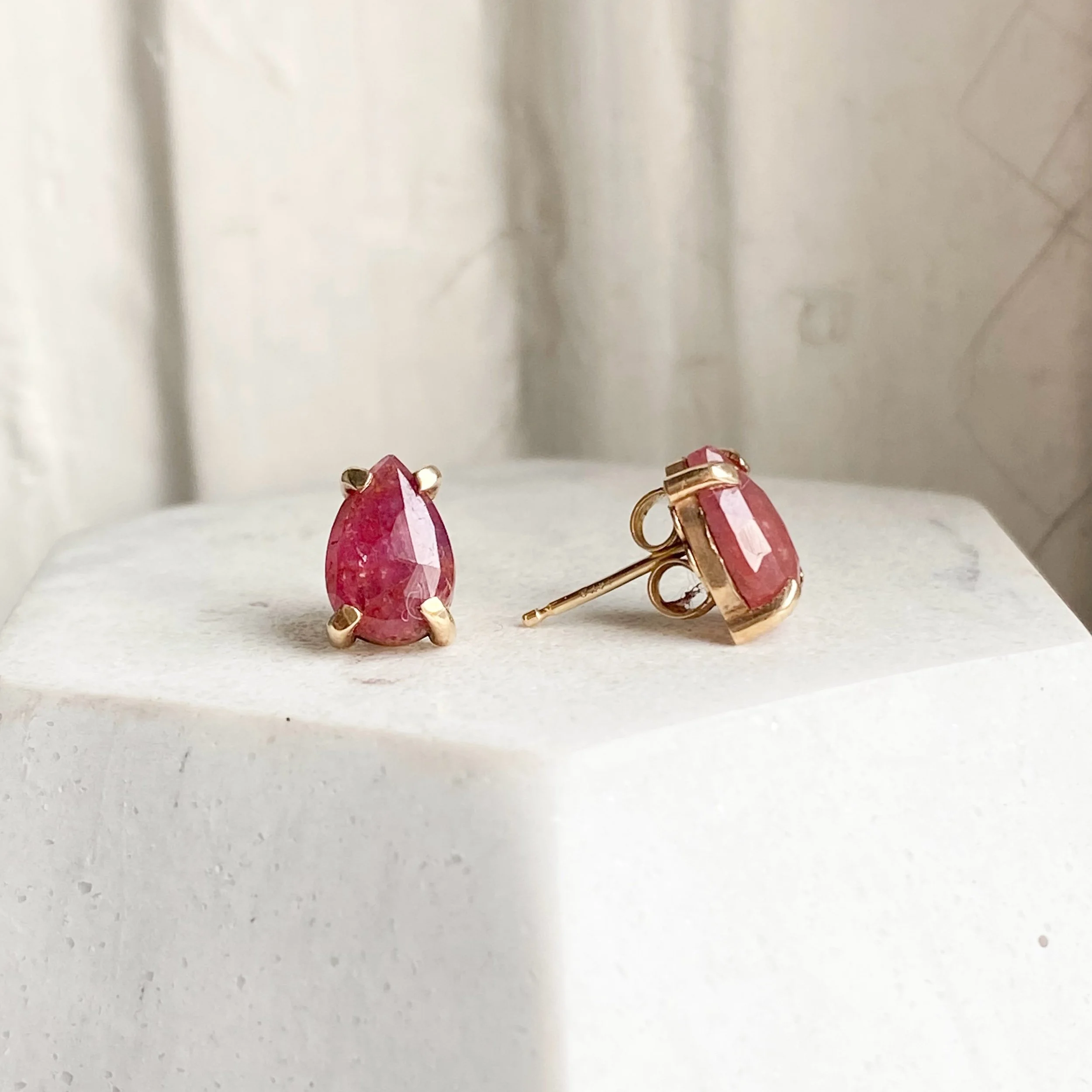ruby rose cut pear studs in 14k yellow gold claw setting made by Kim Drosdick Toronto shown on display side view