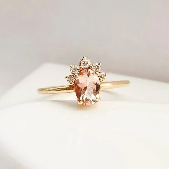 peachy pink oval morganite with little crown of Canadian diamonds claw set in 14k yellow gold narrow rounded band on prop dish Kim Drosdick Jewellery Toronto
