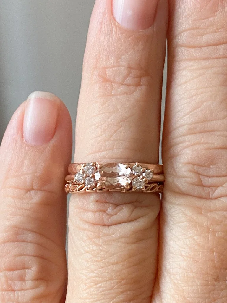 east west claw set oval morganite with mixed size round mirrored canadian diamond clusters shown on hand and raised to allows future flush wedding ring 14k rose gold Kim Drosdick Jewellery Toronto