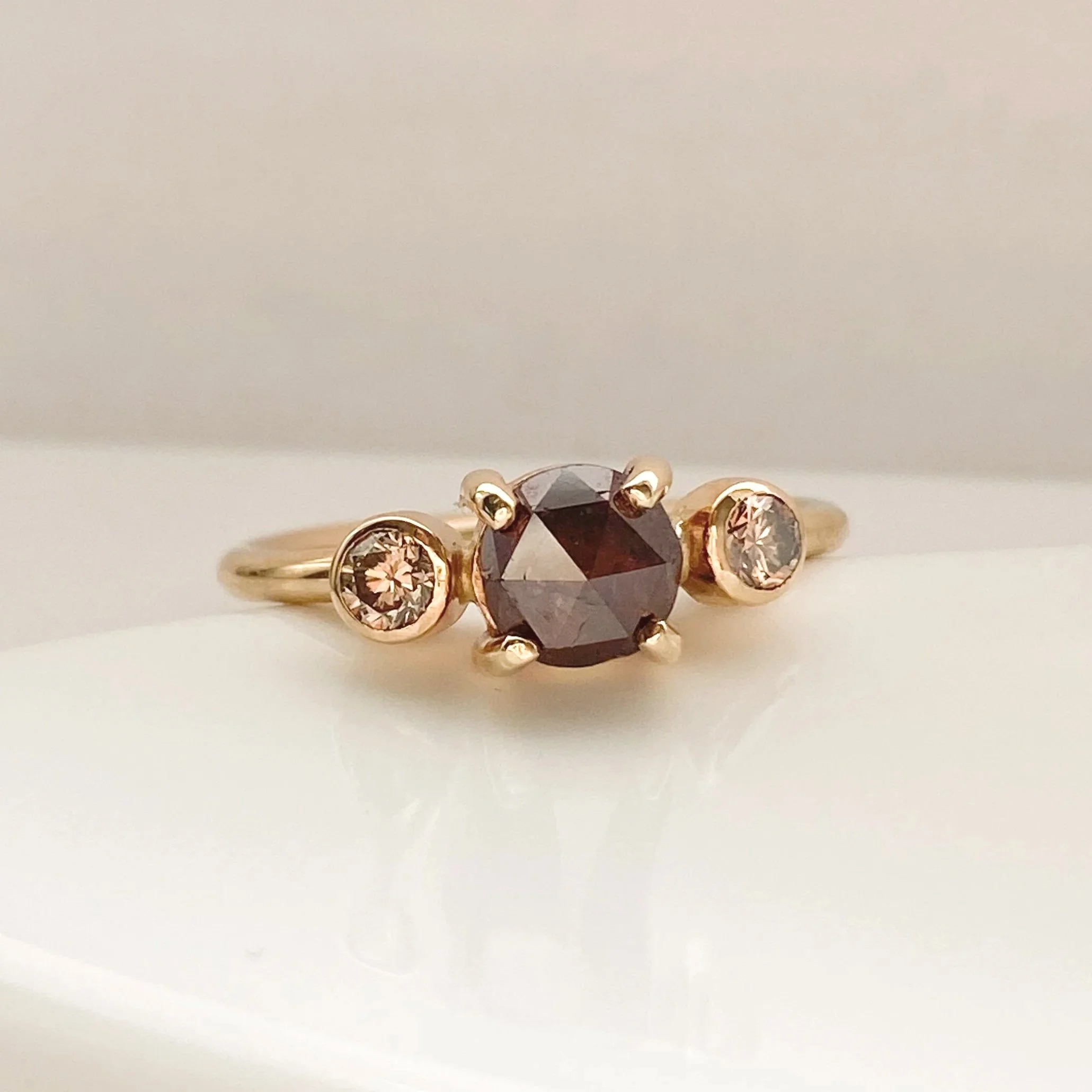 round deep red rose cut claw set diamond flanked by bezel set champagne brilliant cut diamonds 14k yellow gold on dish Kim Drosdick Jewellery Toronto