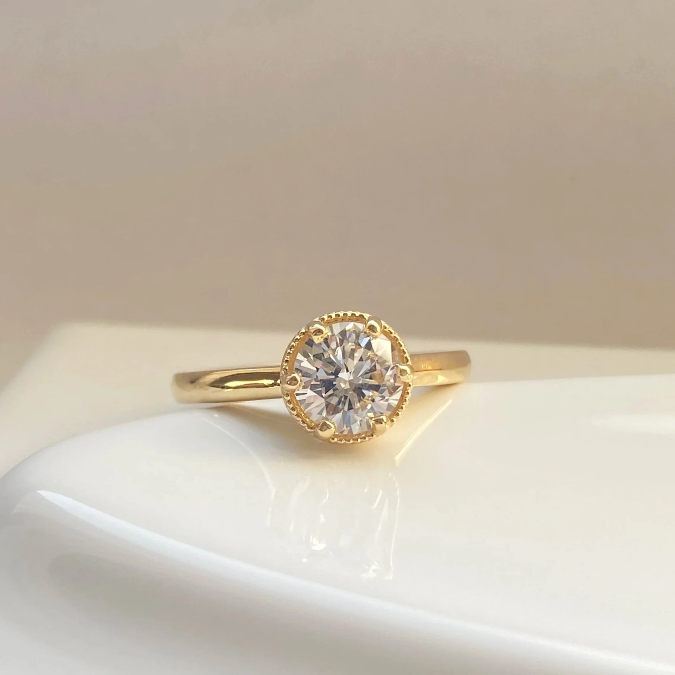 round millgrain claw set solitaire 4 prong engagement ring made in Toronto by Kim Drosdick lab diamond in 14k yellow gold on prop