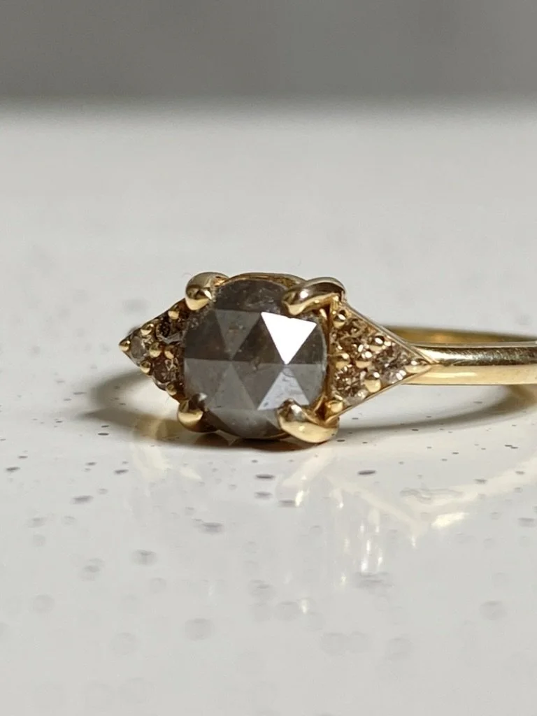dark grey rose cut diamond engagement ring with diamond trio triangle sides 14k yellow gold on dish close up Kim Drosdick Jewellery Toronto