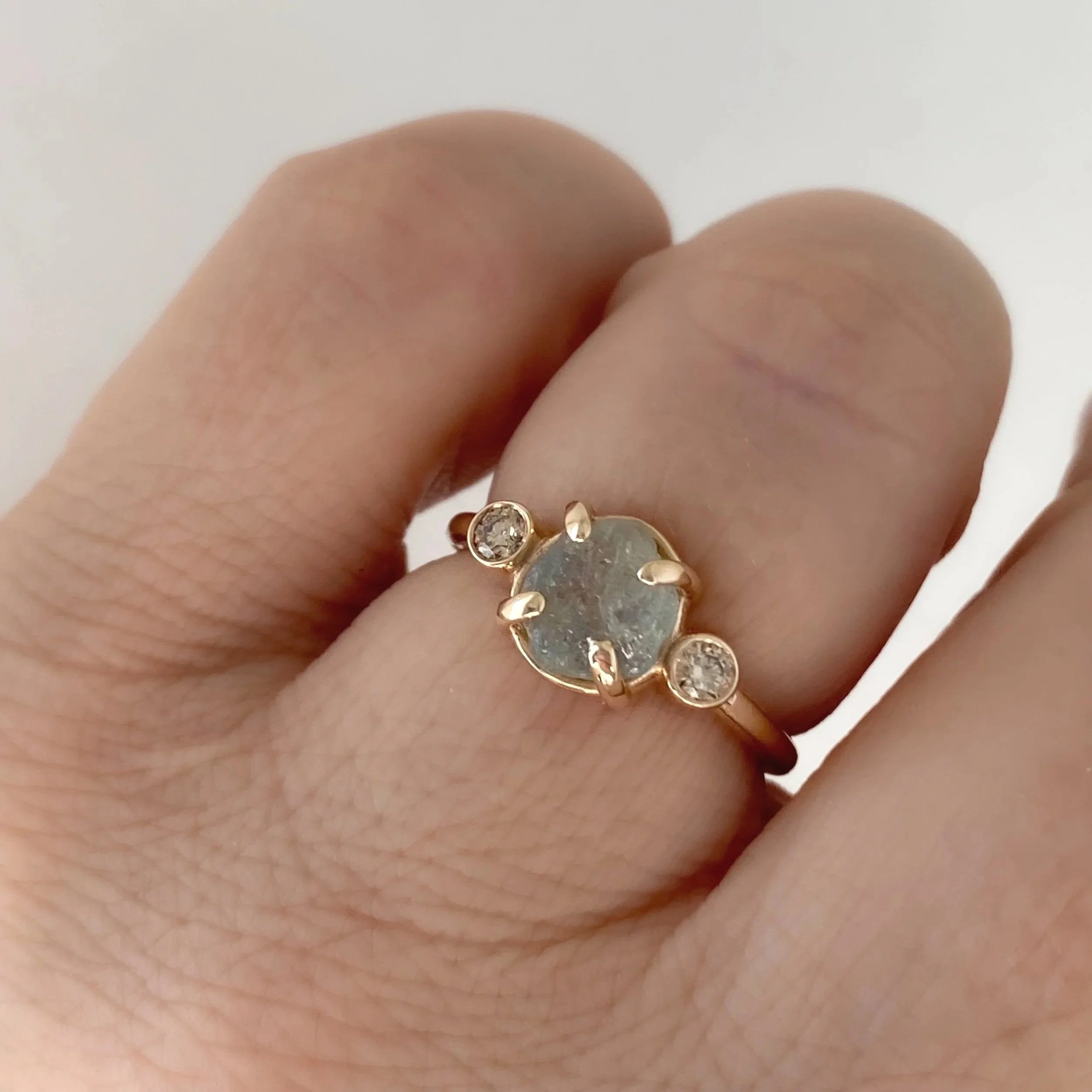 round Montana minty blue green claw set engagement ring with side bezel set champagne diamonds 14k yellow gold front view on hand Kim Drosdick Jewellery Toronto