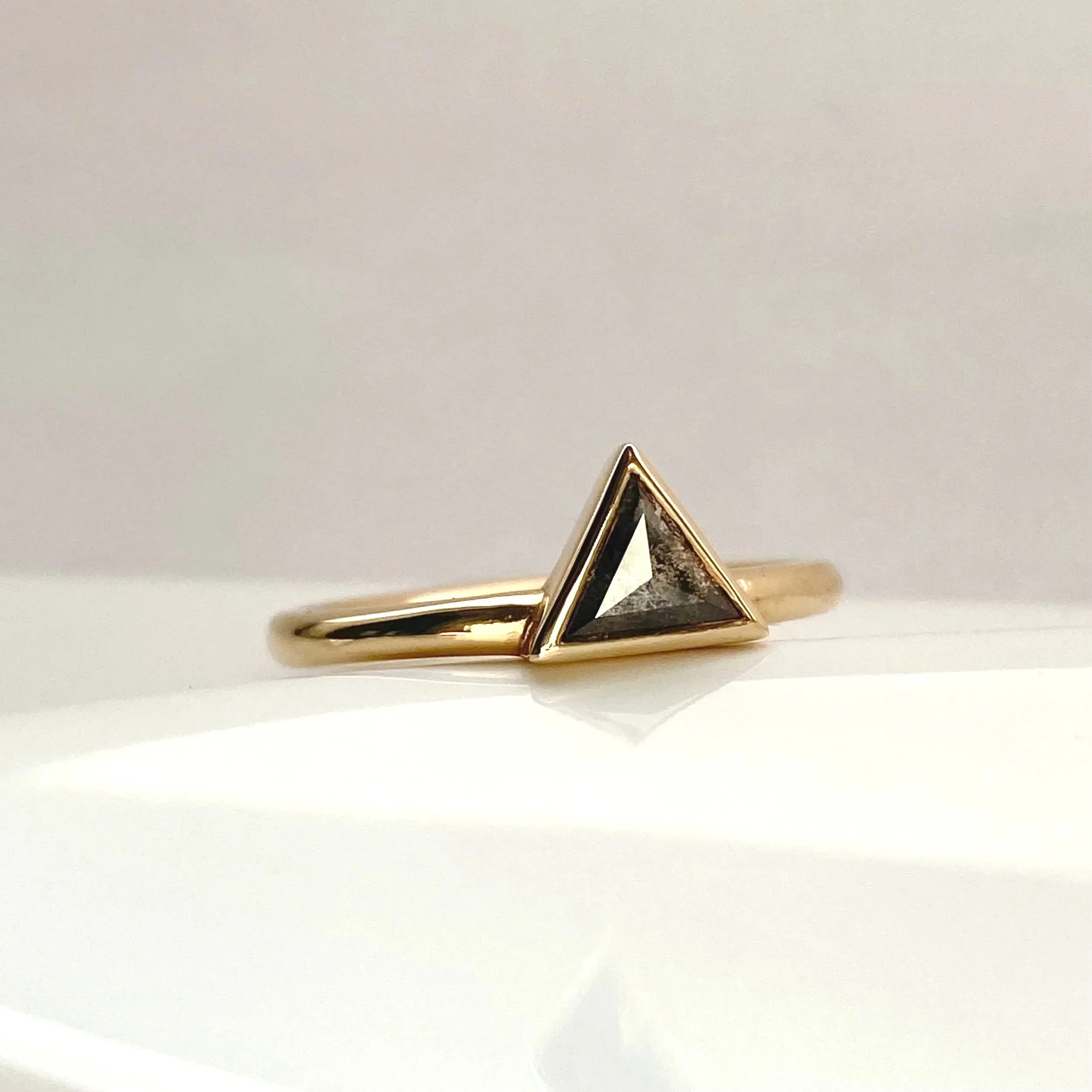 darker triangle salt and pepper diamond bezel set off side bottom justified to round wire band 14k yellow gold on dish Kim Drosdick Jewellery Toronto