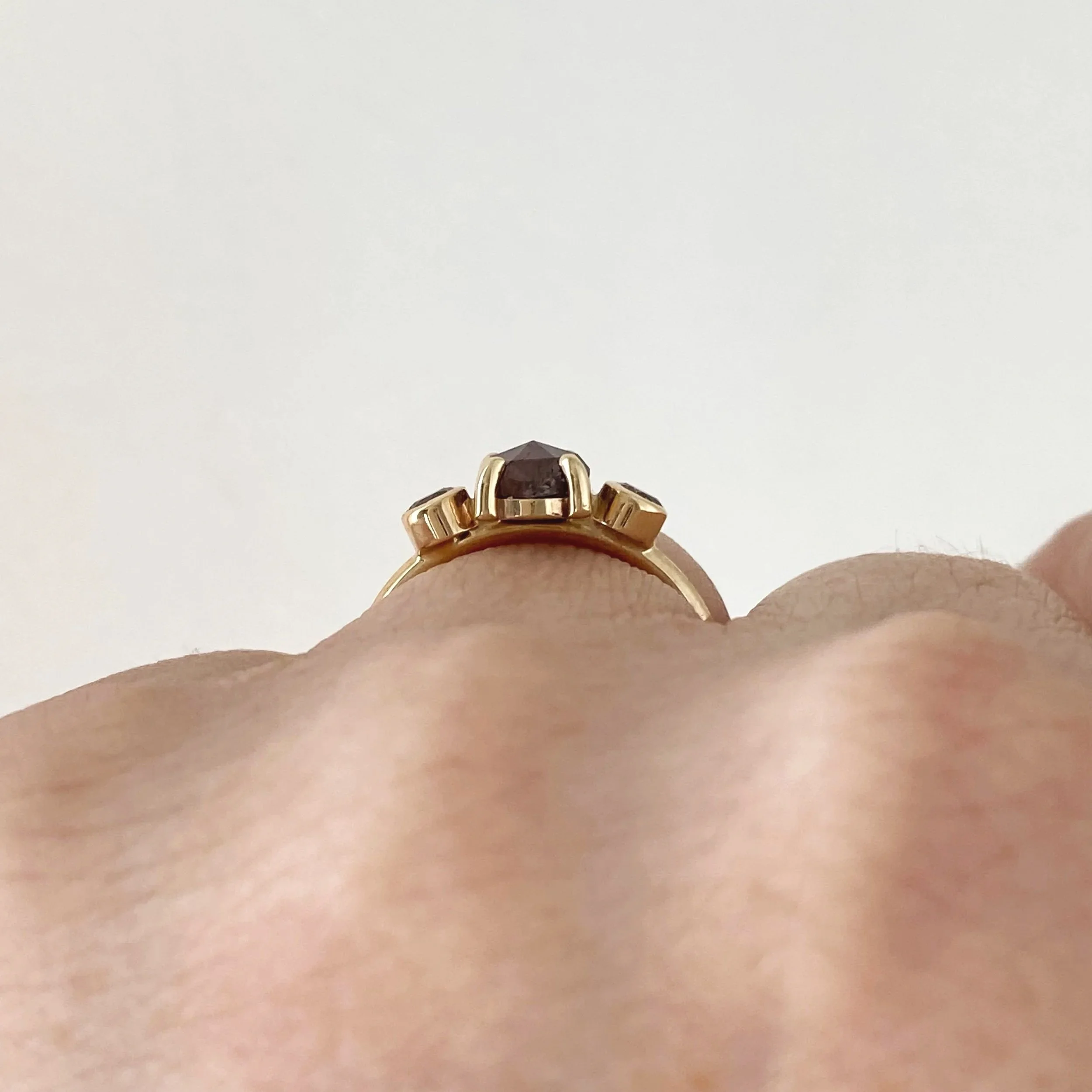 round deep red rose cut claw set diamond flanked by bezel set champagne brilliant cut diamonds 14k yellow gold through finger view Kim Drosdick Jewellery Toronto