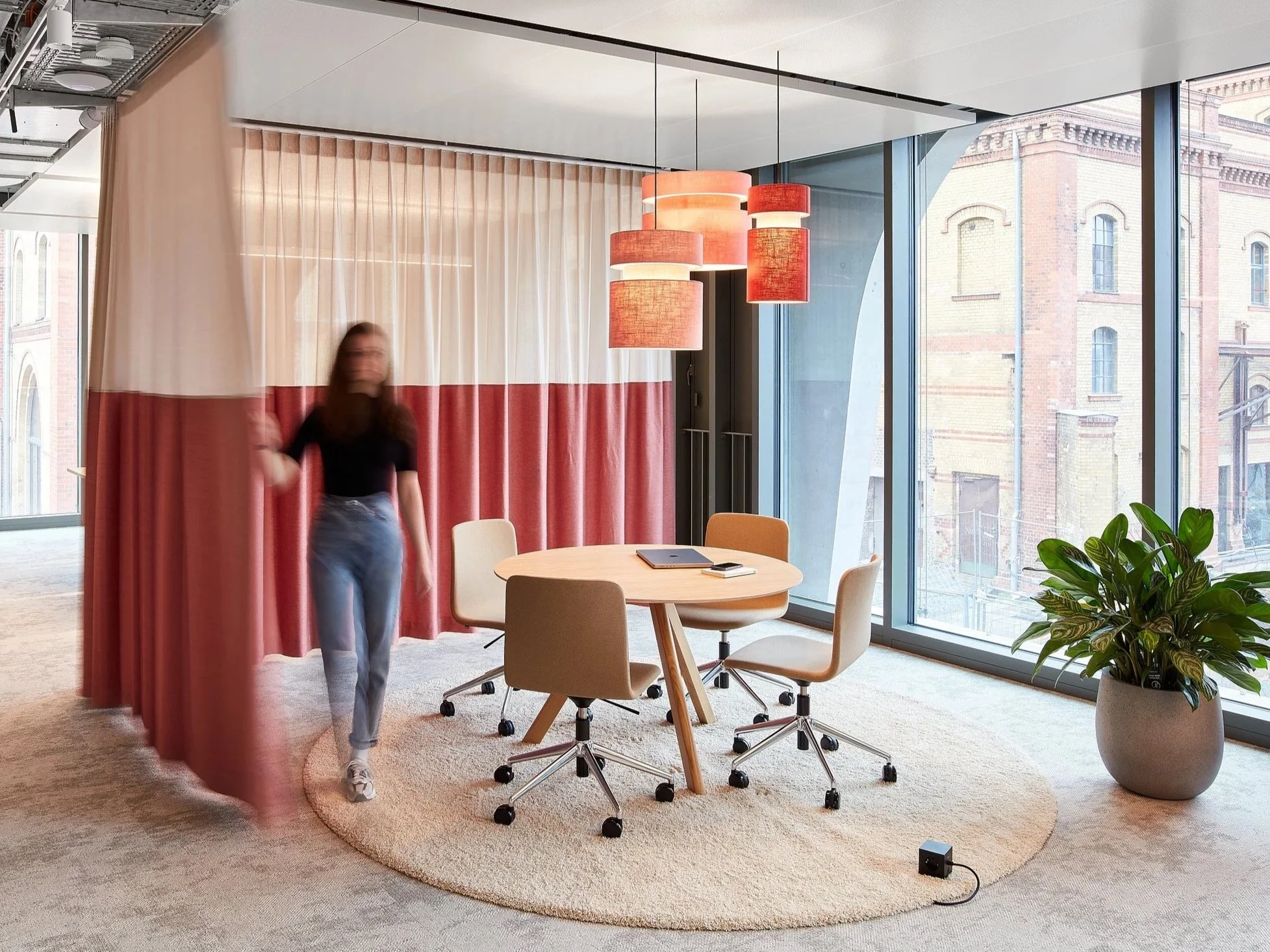 informeller Meetingraum, Abtrennung mit Vorhang rot, runder Tisch, Teppich, rote Pendelleuchten