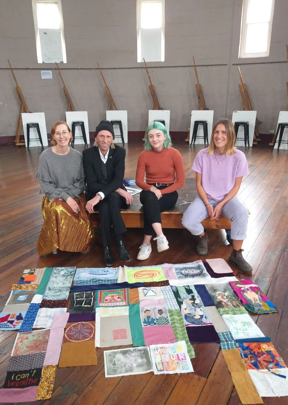 NAS lecturer Molly Duggins, alumni Reg Mombassa, and students Rani Matthews and Anna Mould with the Corona Quilt as work in progress, in the NAS Chapel. Photo: Jacqui Taffel