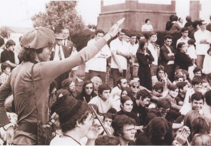 Un asistente levanta el brazo haciendo el saludo fascista. Al fondo, un hombre con gafas oscuras luce una gorra con una esvástica