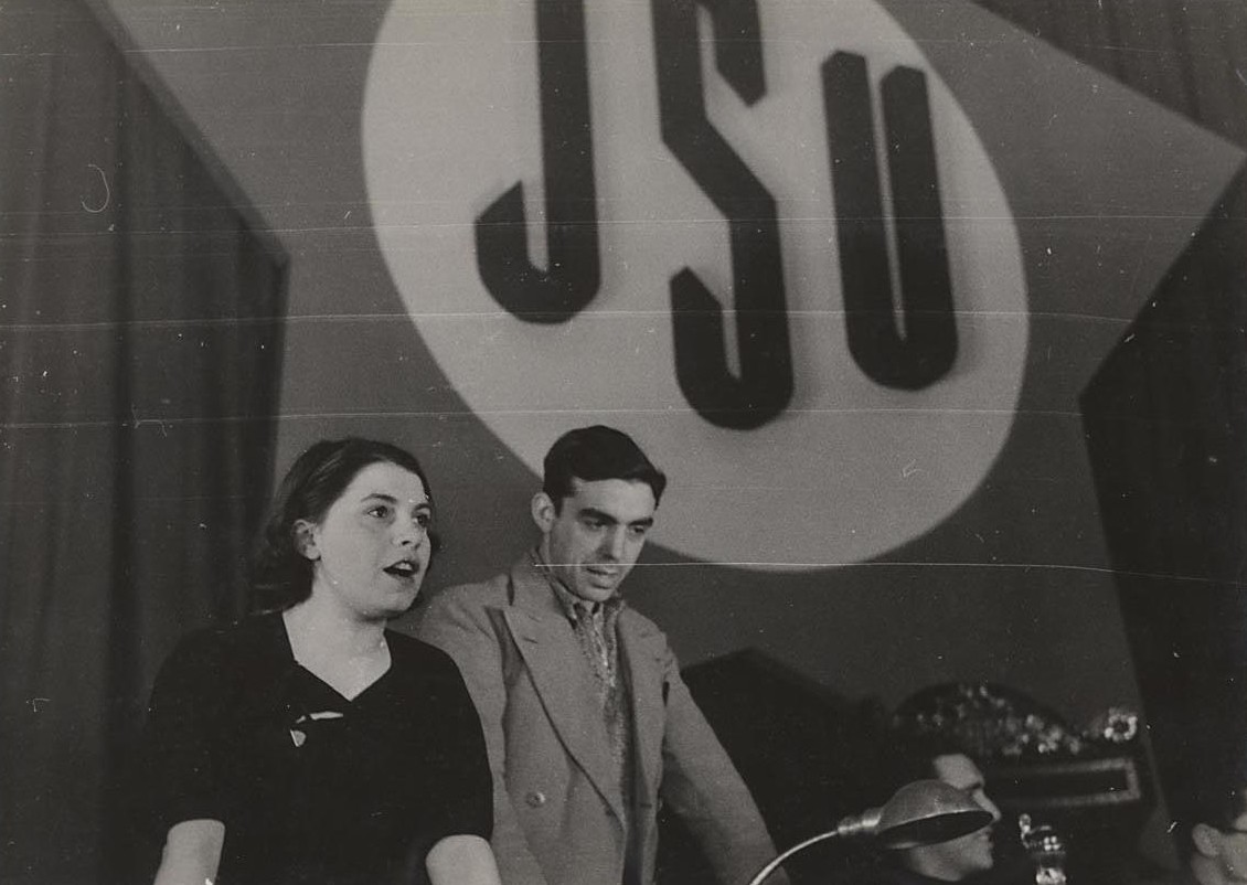 Trifón Medrano, de pie y a la derecha de la oradora, durante un acto de las JSU