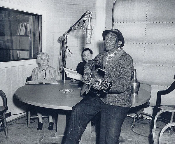El histórico bluesman Mississippi John Hurt junto a varios folcloristas durante una grabación para la Library of Congress Recording Laboratory (1964). Fotografía: Library of Congress