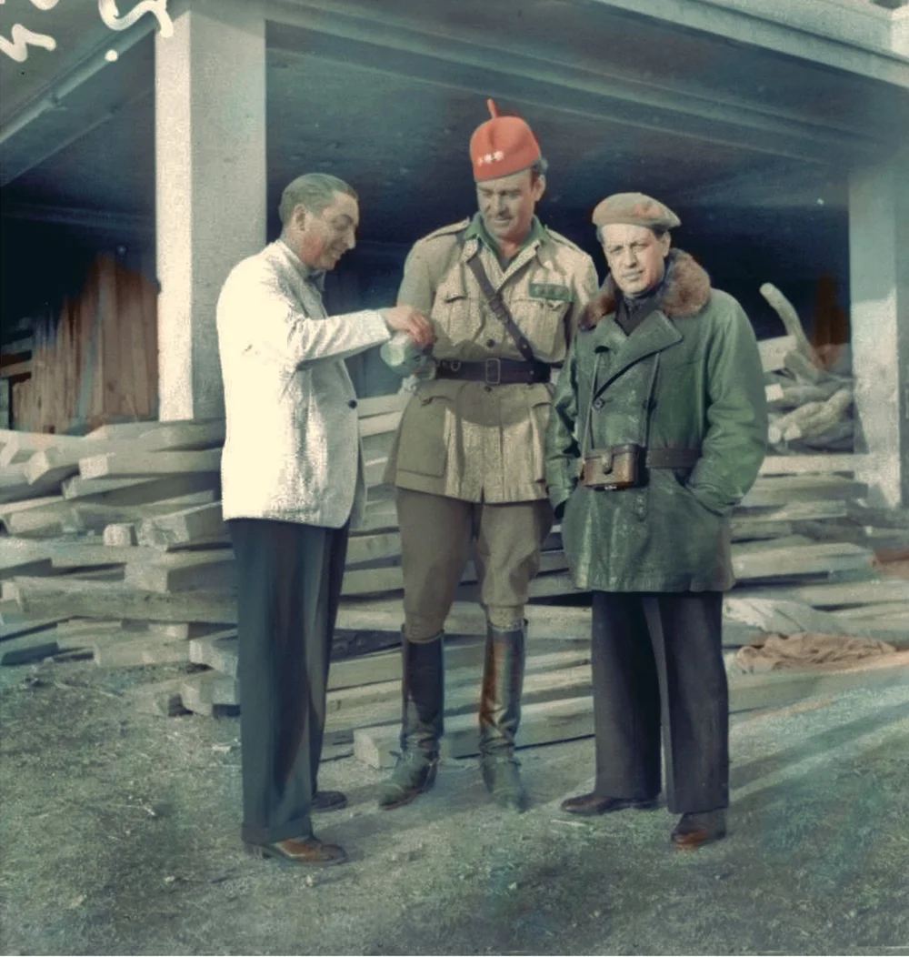 Perico Chicote sirviendo un cóctel de bienvenida al coronel Joaquín Rios Capapé y al fotógrafo Deschamps en las ruinas de Ciudad Universitaria (1939). Colección Louis Dechamps. AGA. Coloreada por Tina Paterson