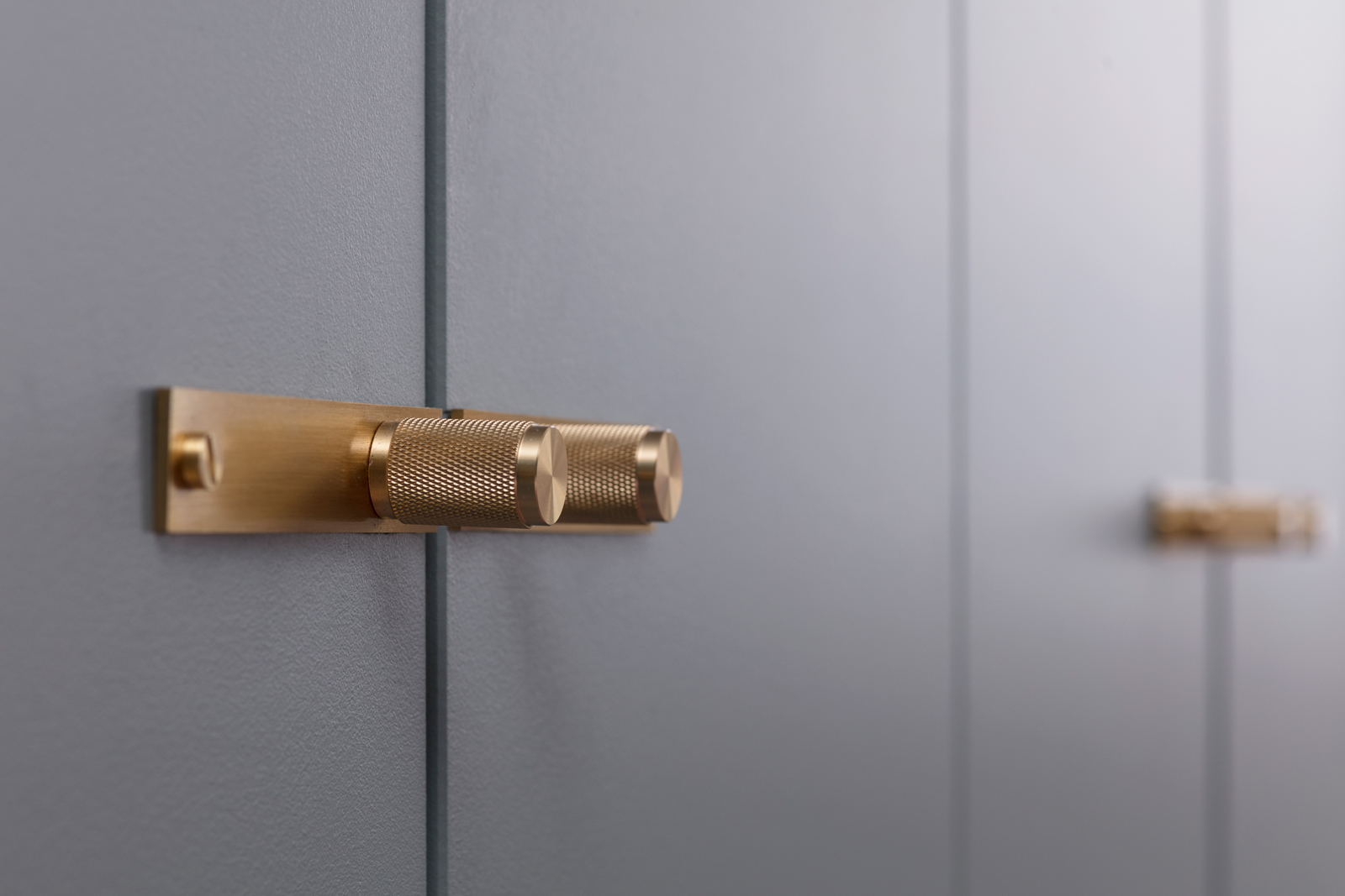 Buster + Punch brass handles on a blue fitted wardrobe