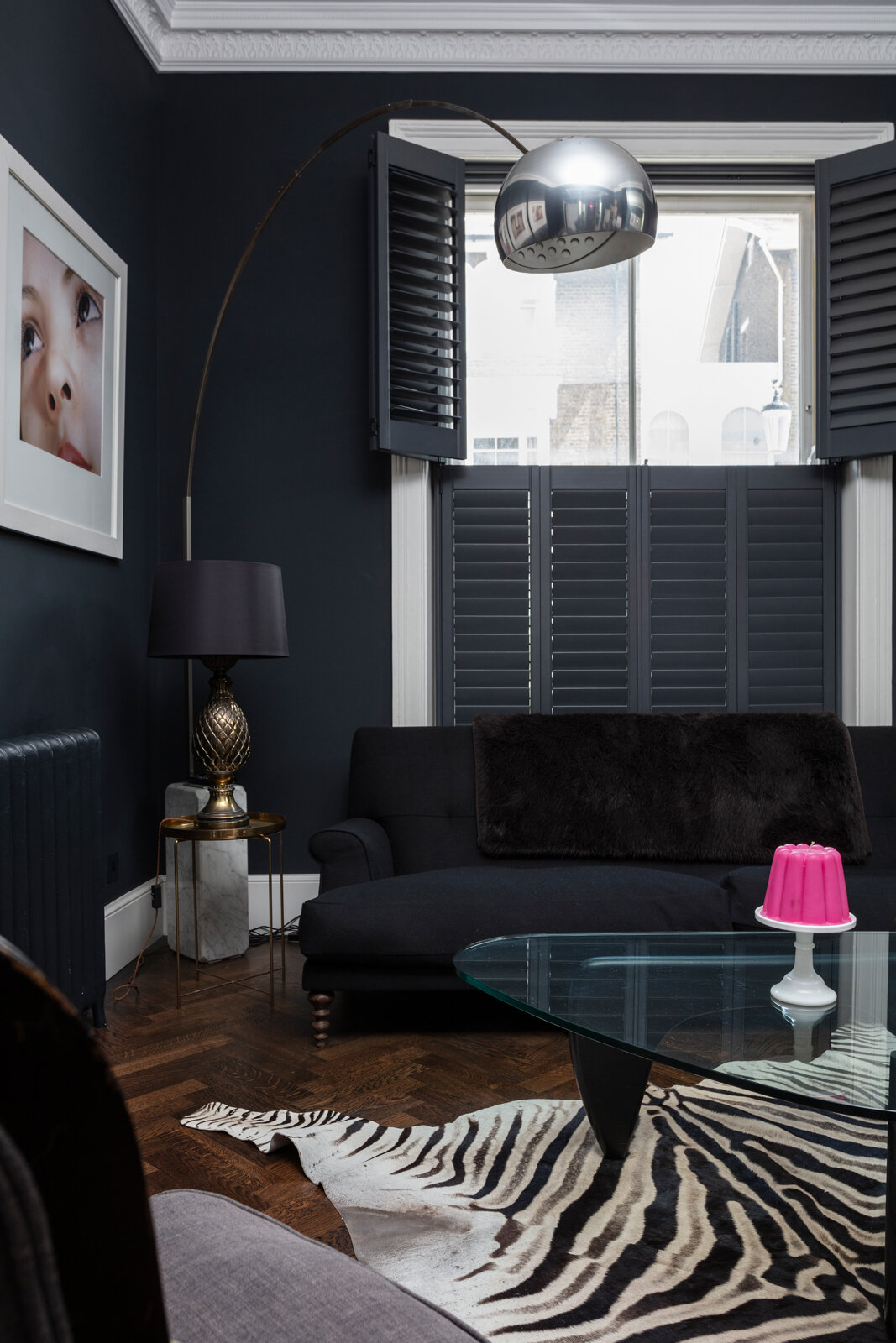 Black sitting room with shutters and zebra skin rug