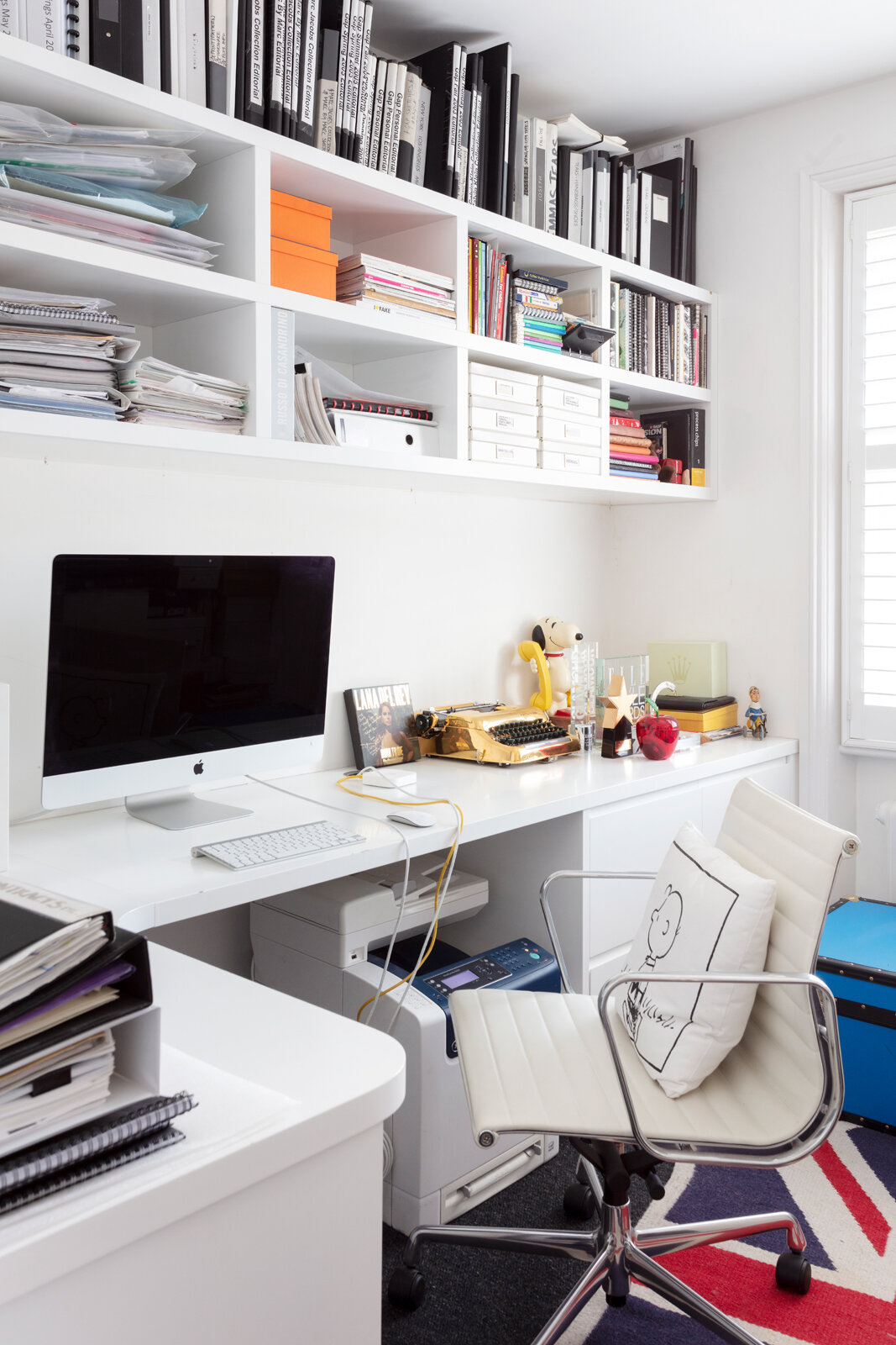 All white home office with gold typewriter and display shelves