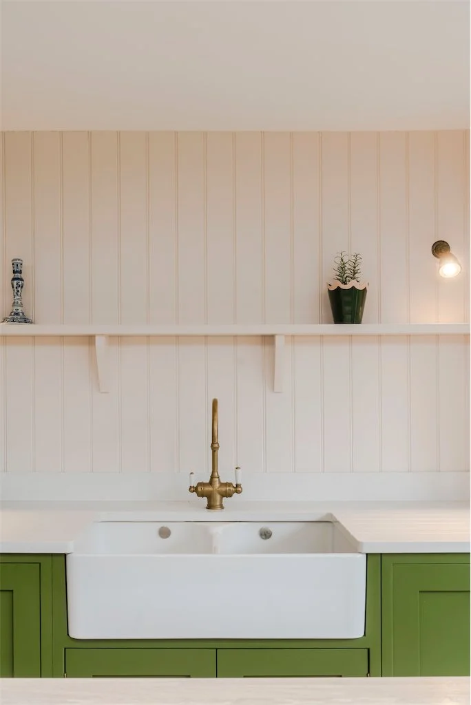 Green kitchen with brass tap and butler sink