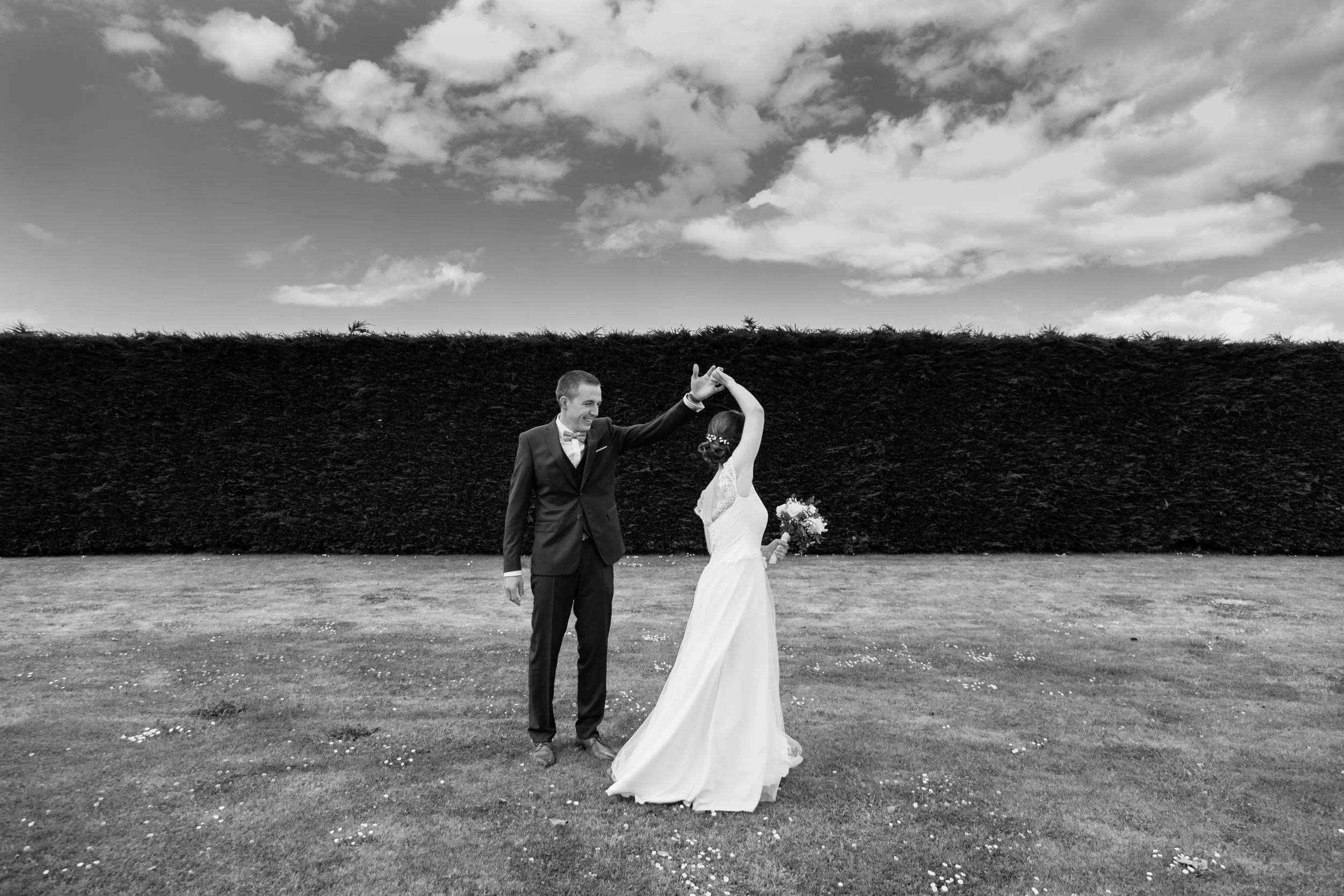 Un marié et une mariée dansant à l'extérieur, avec un ciel nuageux en arrière-plan. Saint-Malo, Bretagne. Casa19