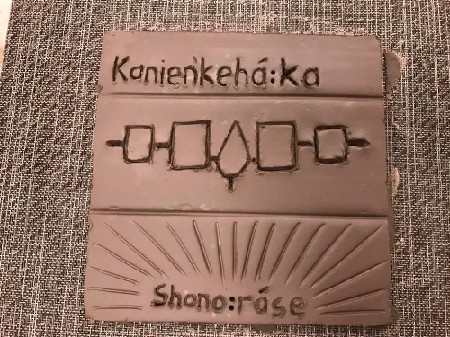 Kanien'keha:ka means People of the Flint (also known as Mohawk People) The middle design is the Iroquois Confederacy symbol, Haudenosaunee, also known as 6 Nations Confederacy. Shono:rase means The New Root, the Mohawk name of the tile maker. Photo credit: Howard Adler
