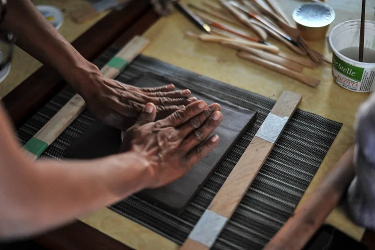 Pressing an image into the wet clay. Photo credit: Andrew Alexander