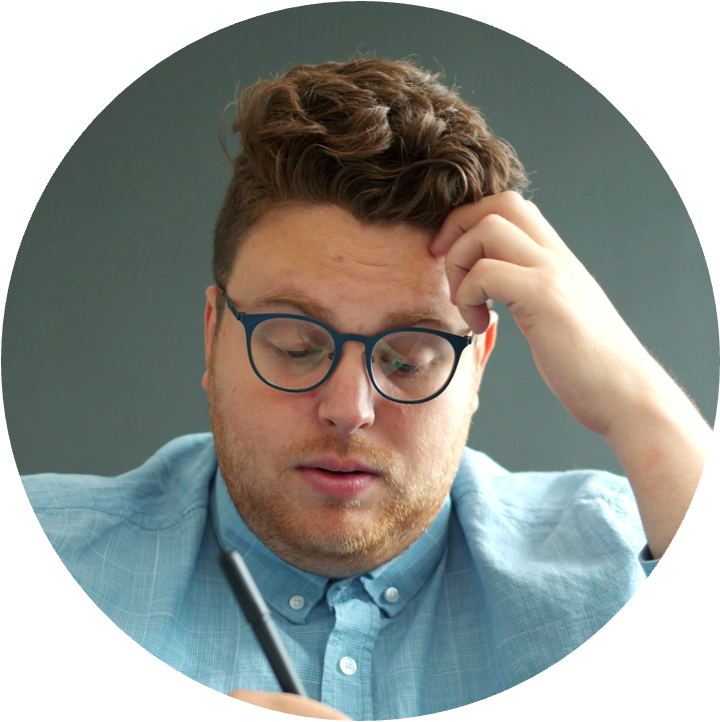 A person in a collared shirt and glasses holding their head