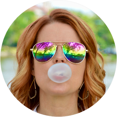 A person wearing sunglasses and blowing a bubble