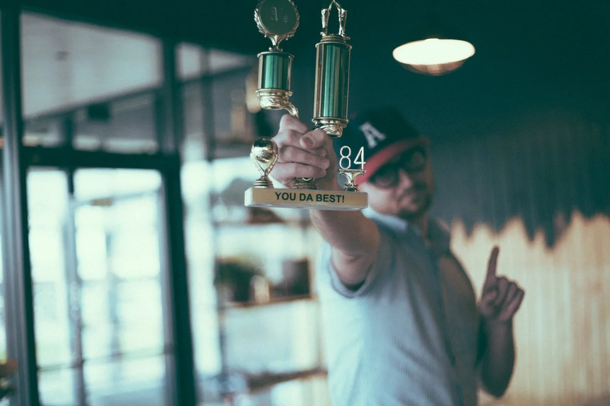 Person holding a trophy with a humorous message and number, in an indoor setting.