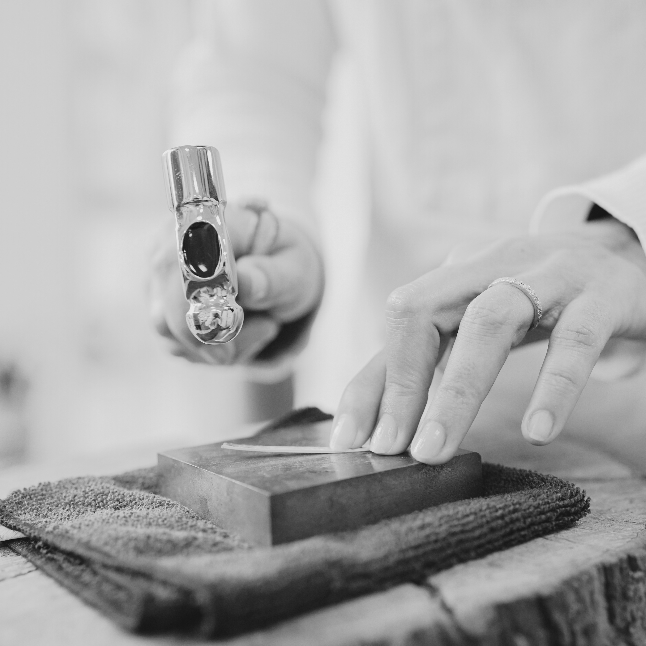 woman's hands use jeweler's hammer to pound small piece of metal on a bench block how to money with artwork cynthia deis consulting